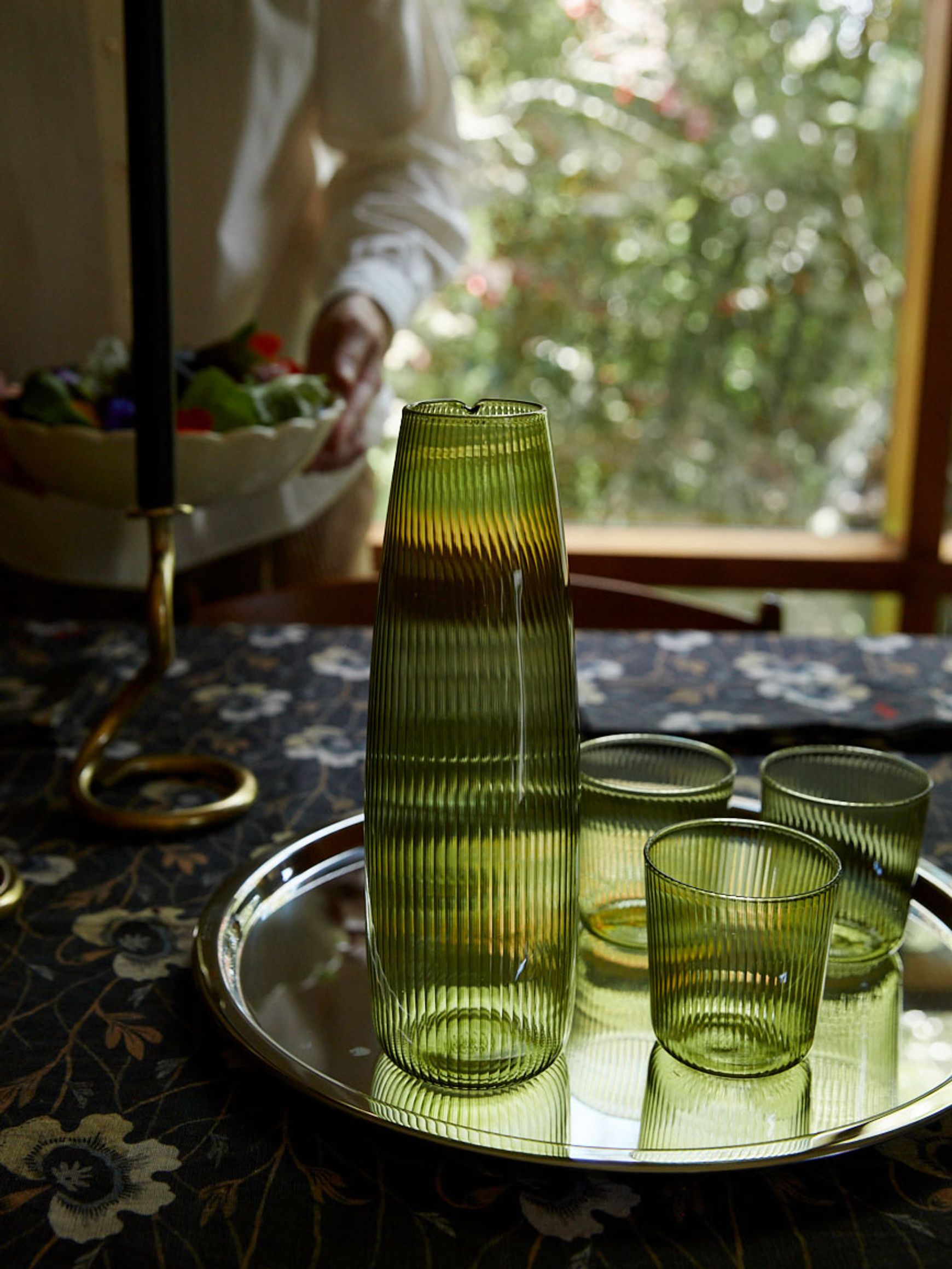 Green glass carafe and glasses on a tray in a table setting