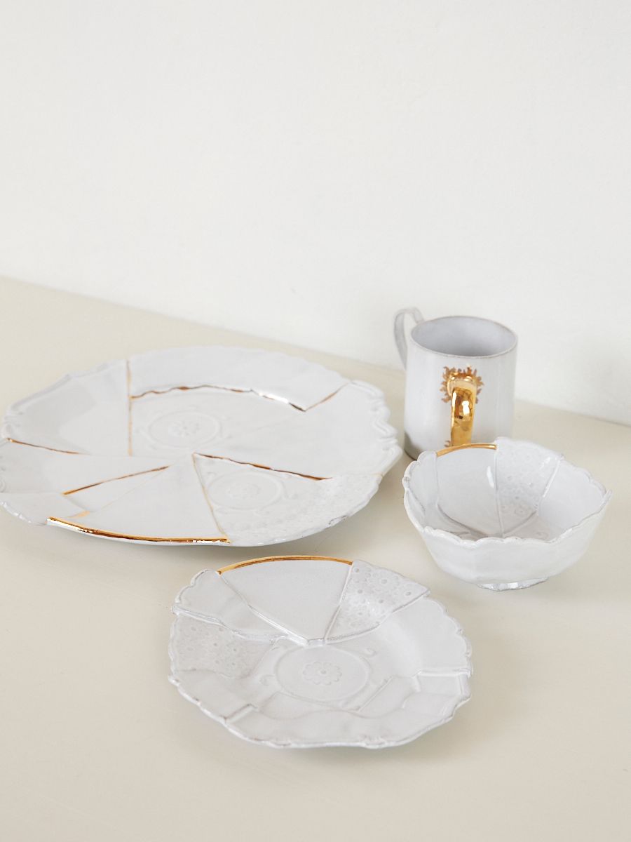 one large plate and one small plate sit next to a white bowl and gold accented mug 