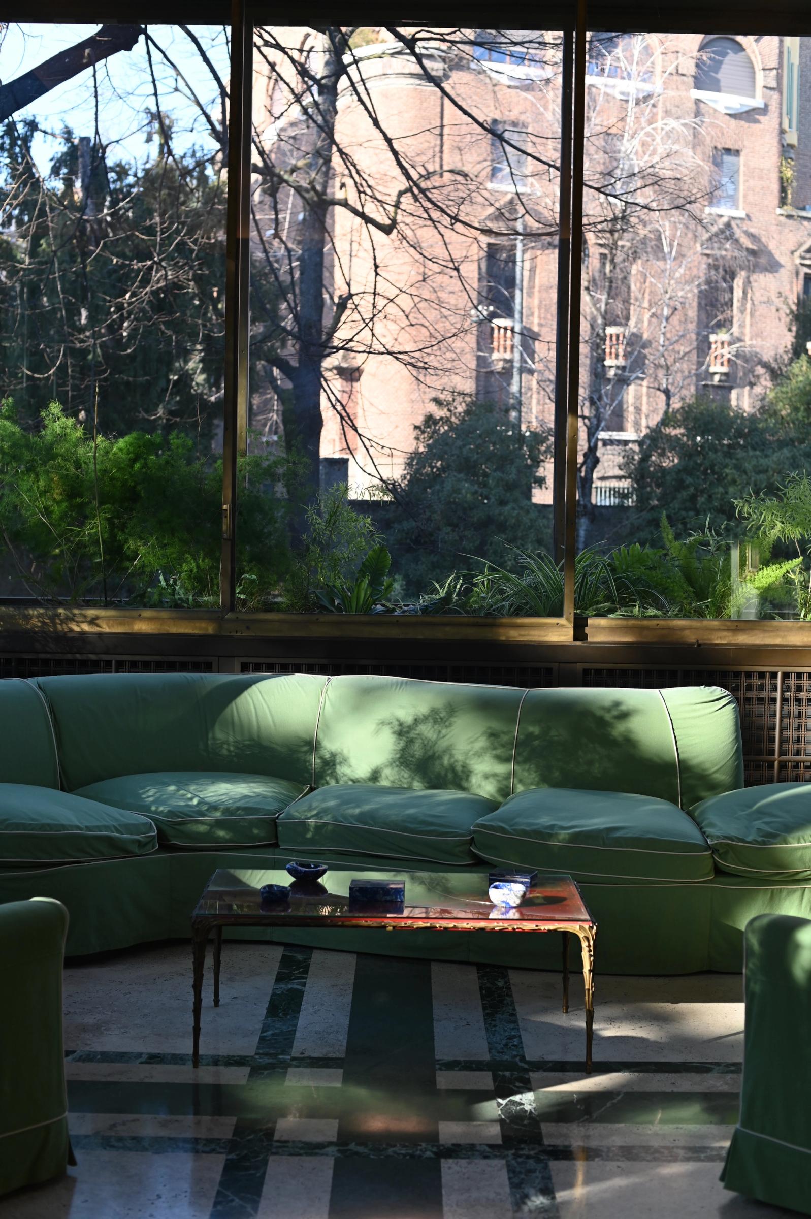 green couches lined underneath a window looking over the garden