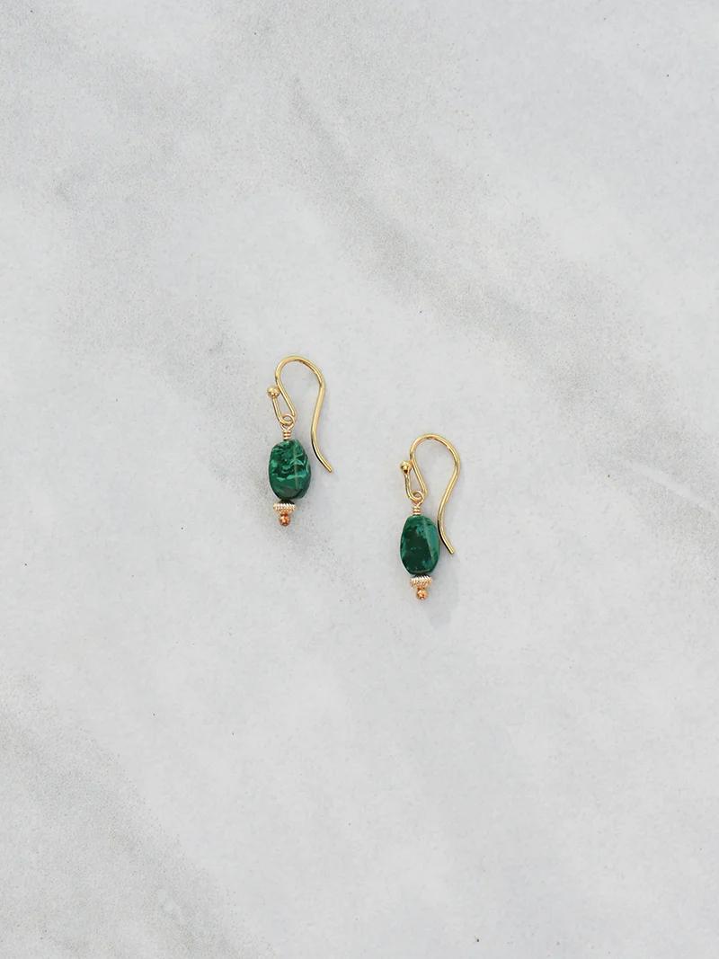 Gold hoop earrings with green gemstones on gray background. Oval stones attached with intricate gold detail.