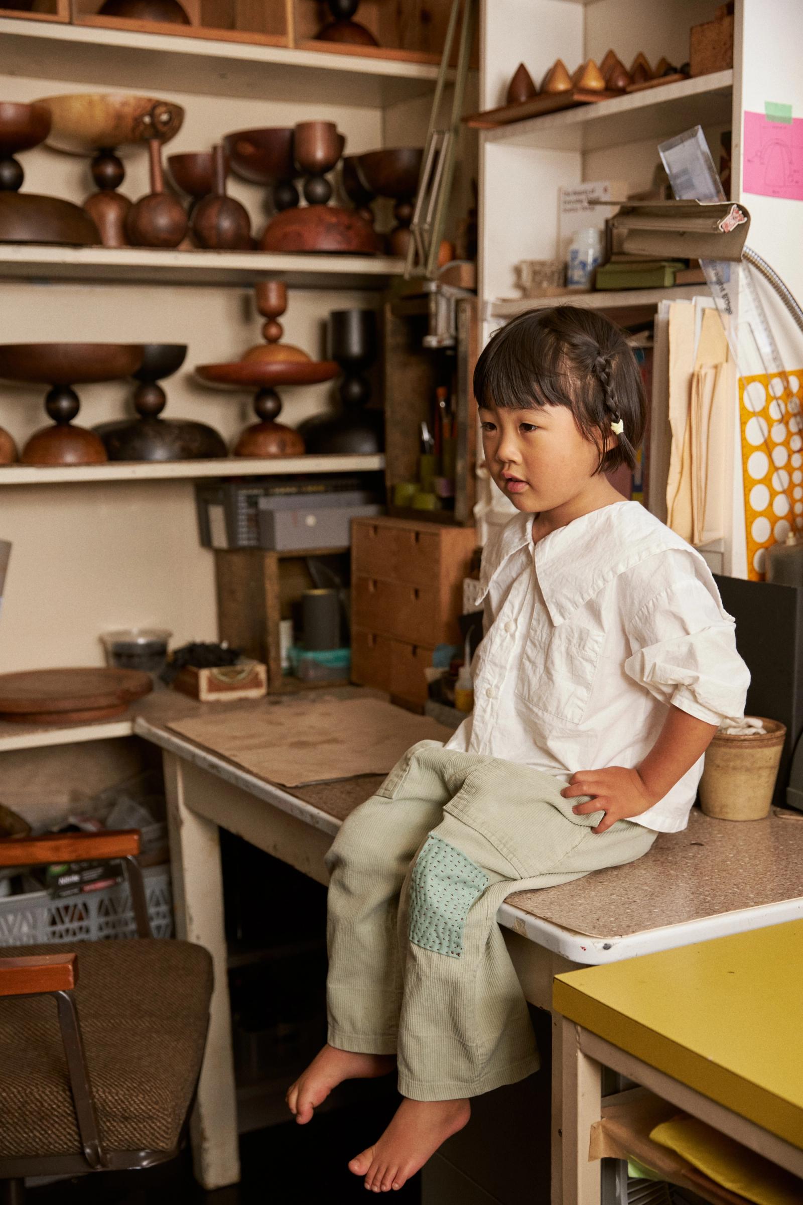 Eden sits on her dad's workbench surrounded in wood