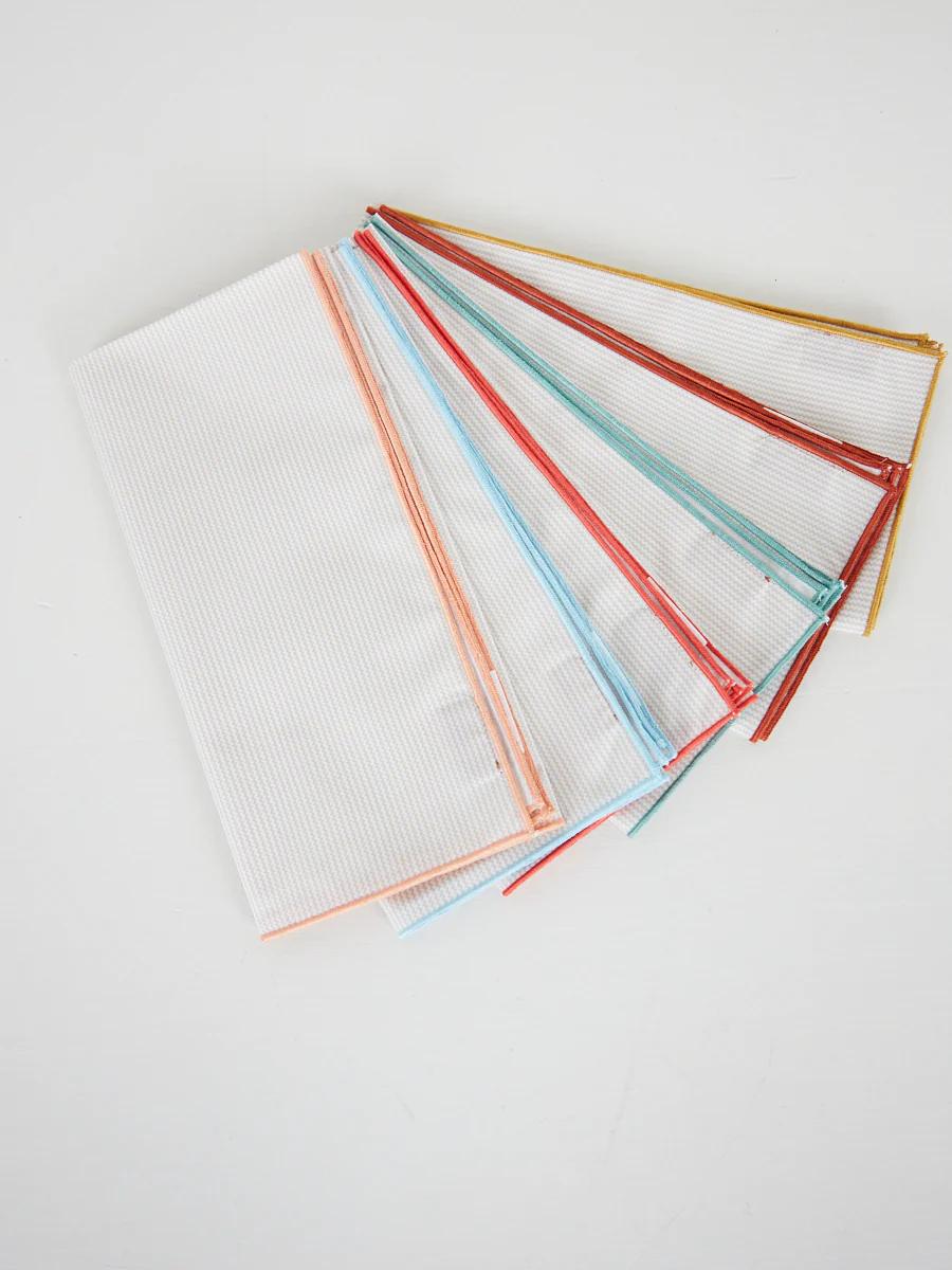 Seven folded napkins with horizontal stripes, colorful borders. Fan arrangement on white surface.