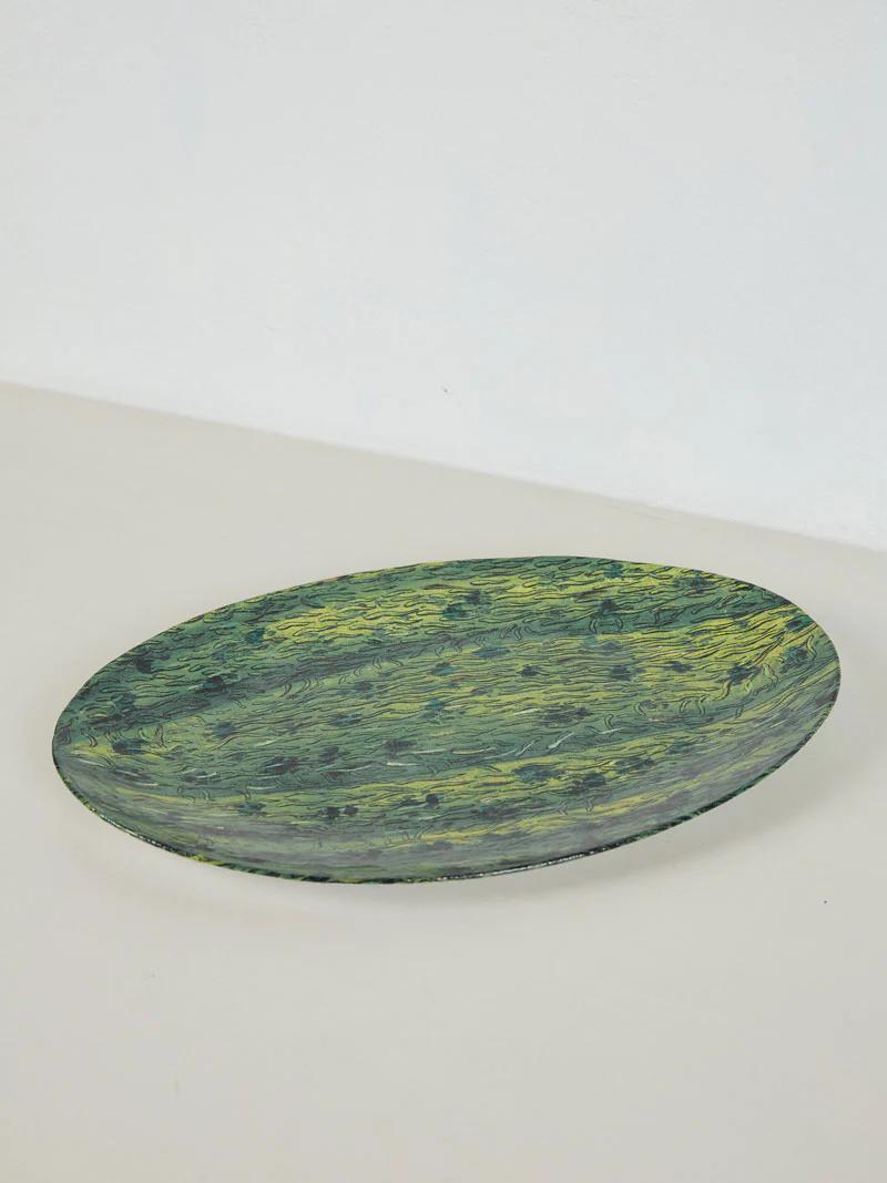 Oval ceramic plate with green and yellow marbled design on light surface. Summer fruit-inspired pattern.