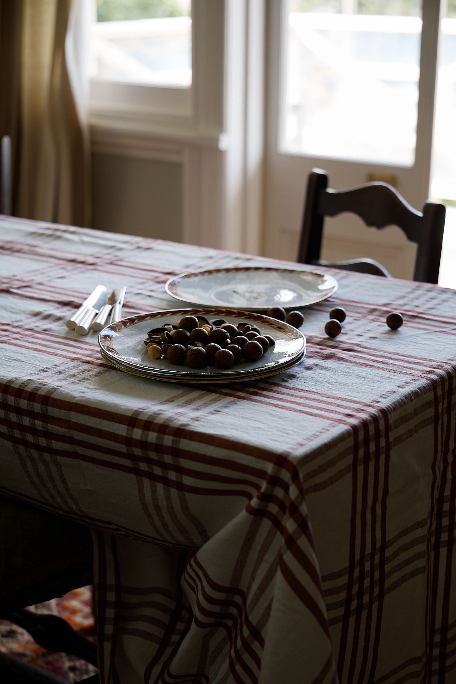 a checkered tablecloth is laid over a table by open doors with plates of hazelnuts on top