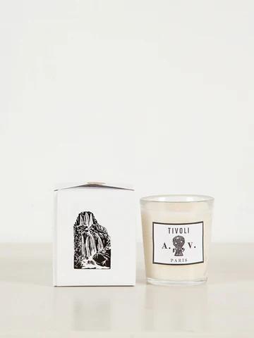 Glass candle labelled "Tivoli A.D.V. Paris" next to white box with statue illustration. Astier de Villatte products set against light background.