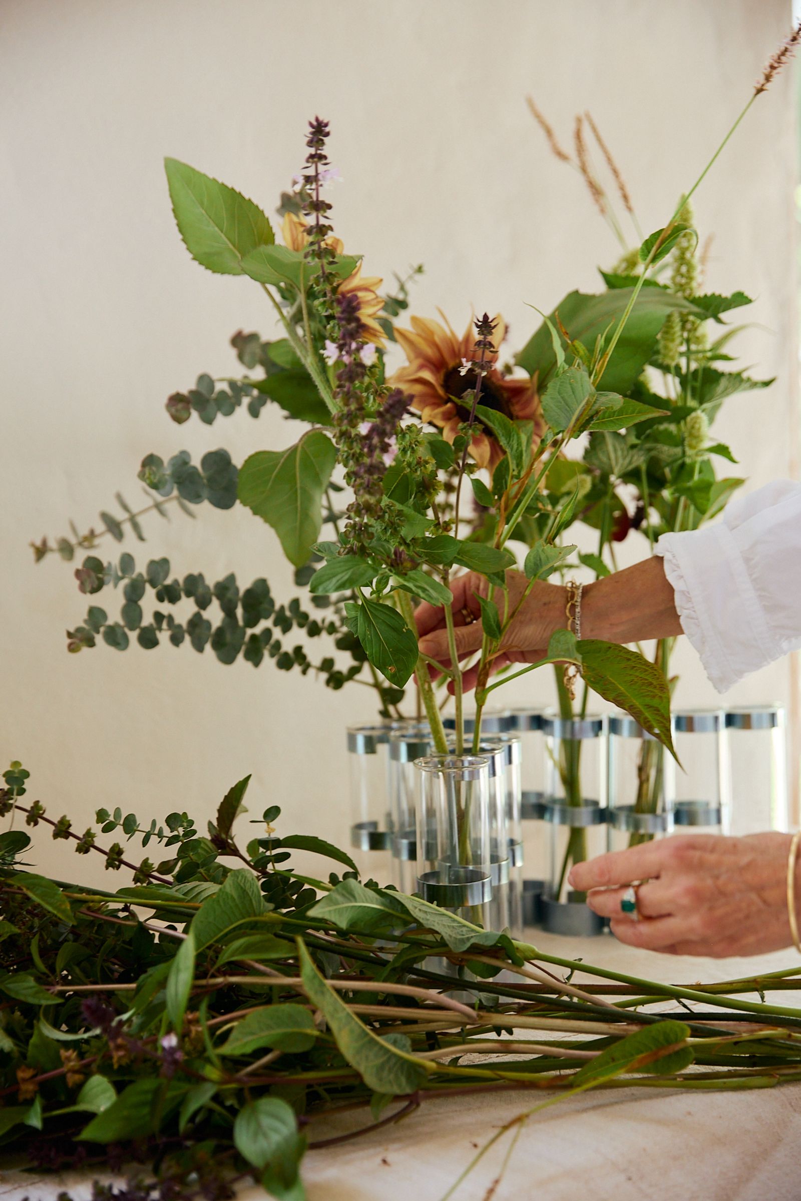 woman arranges fresh flowers into glass vase