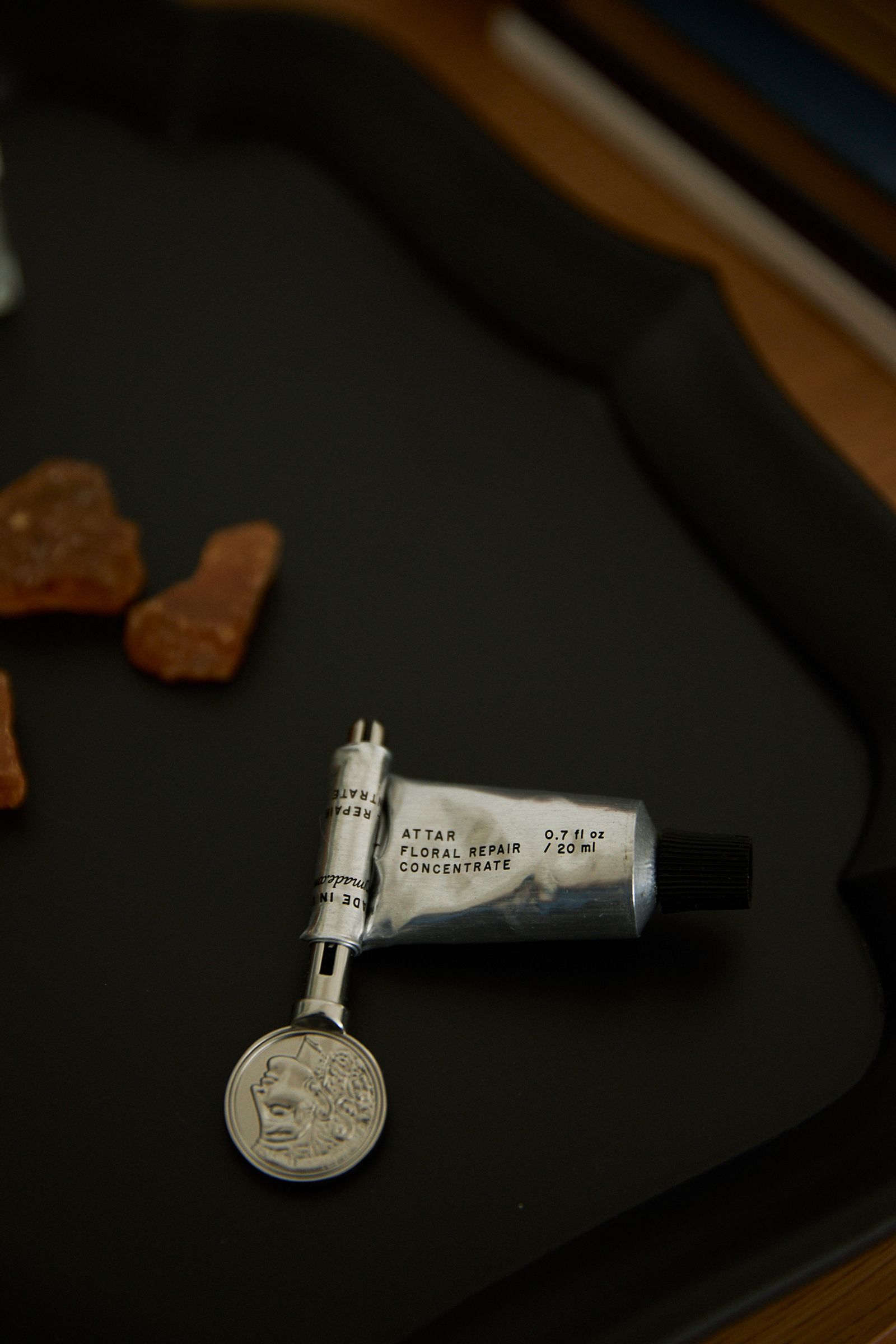 A silver tube of skincare is rolled and in use