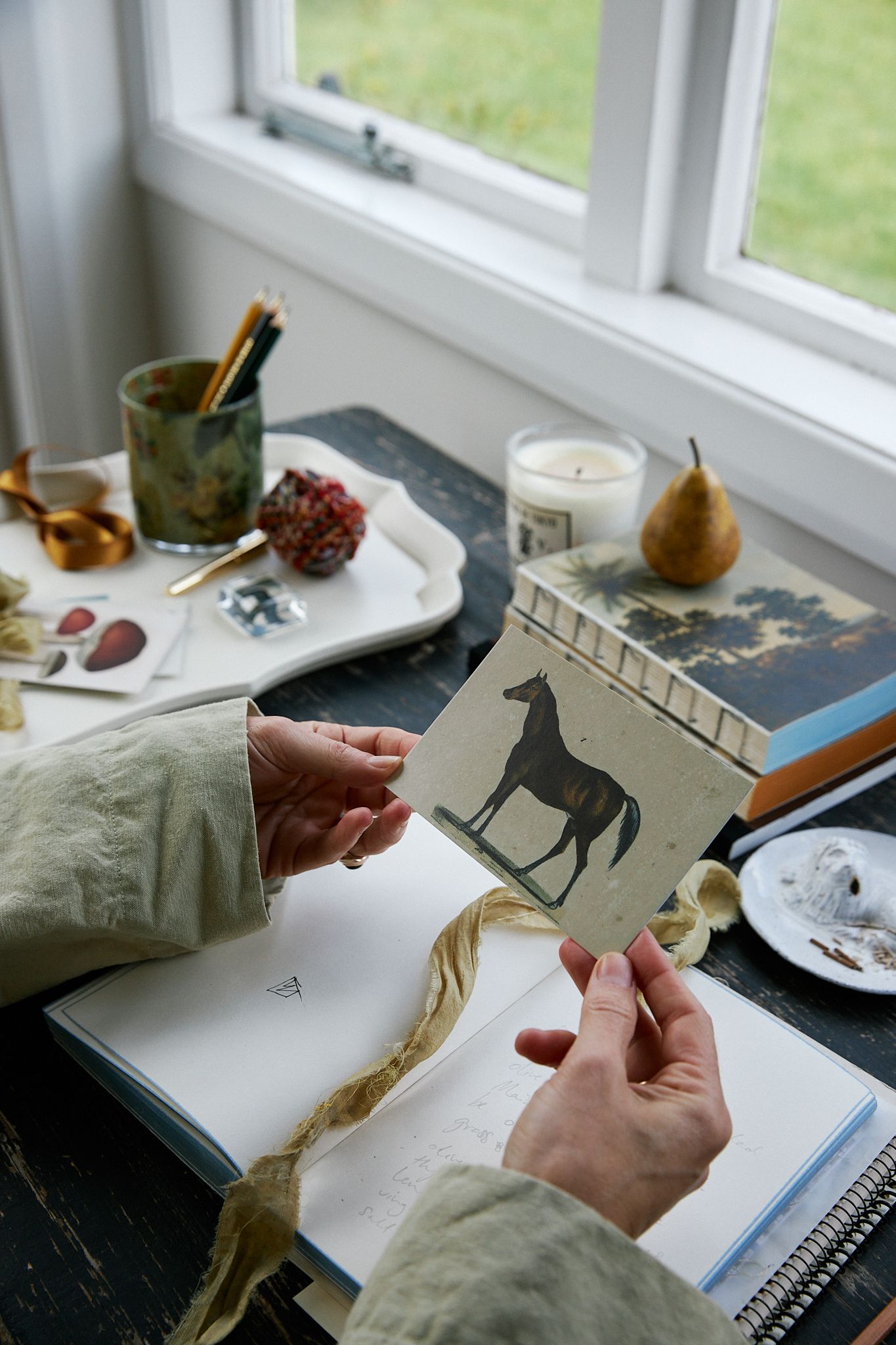 A woman sitting at desk holding a postcard with two hands