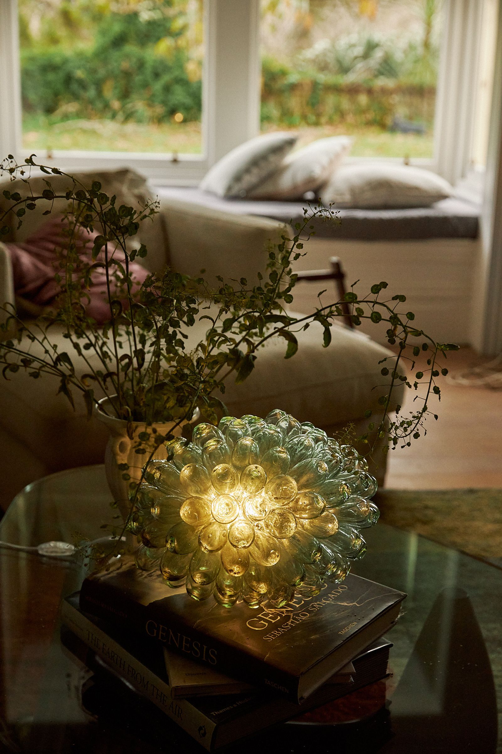 light on coffee table next to a vase of blooms and books