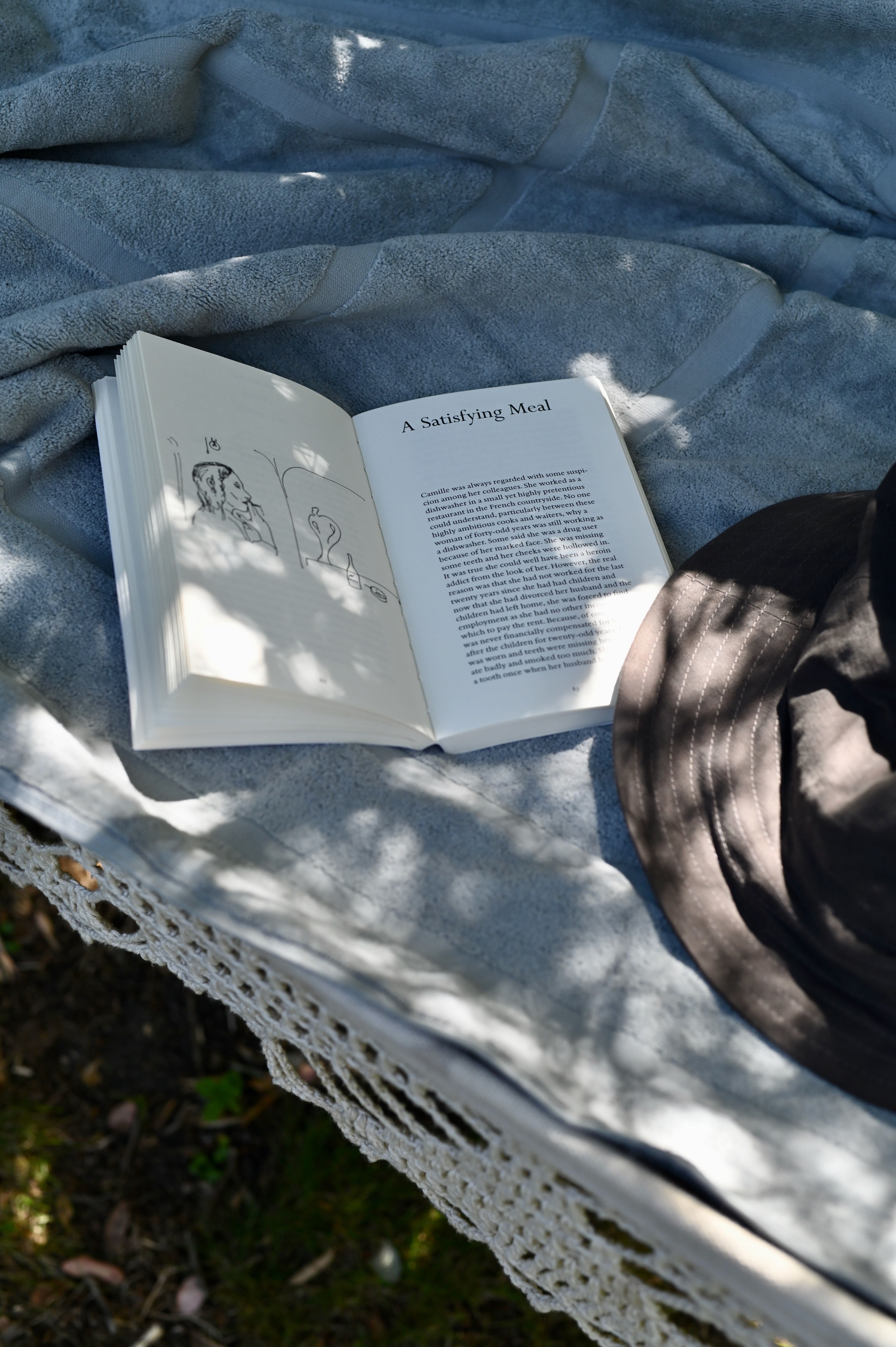 a soft towel and open book upon a white canvas hammock