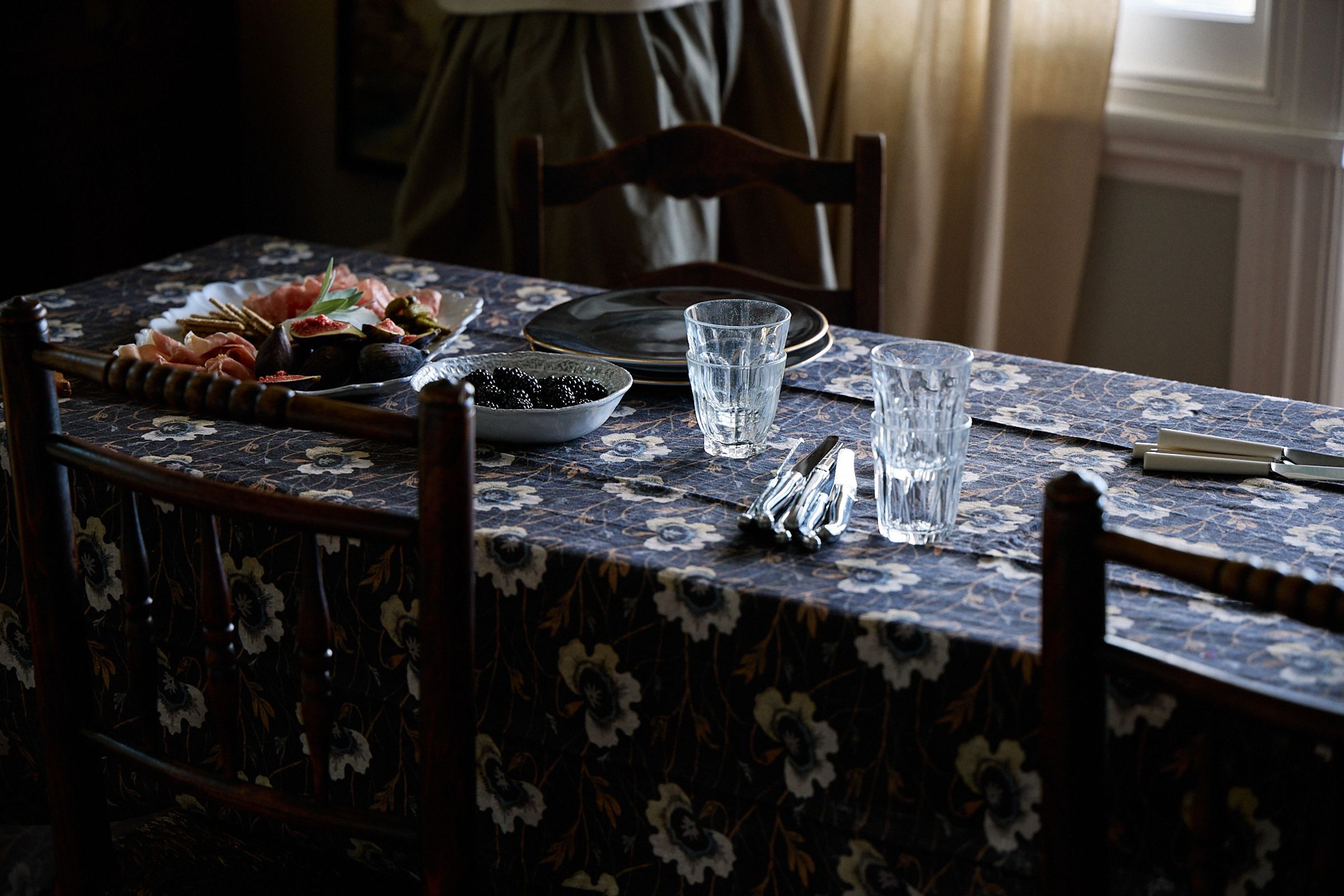 wide shot of table and black wooden chair in natural light with a platter served and cutlery