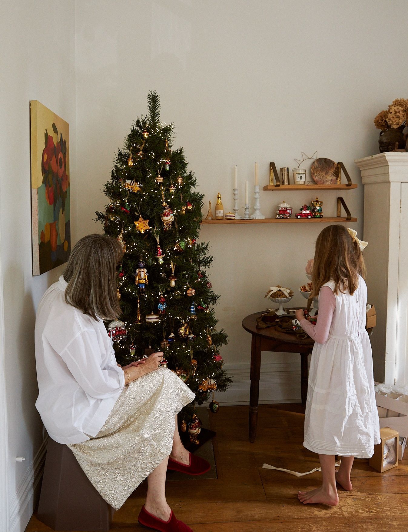 Woman and grand daughter standing in front of decorated Christmas tree