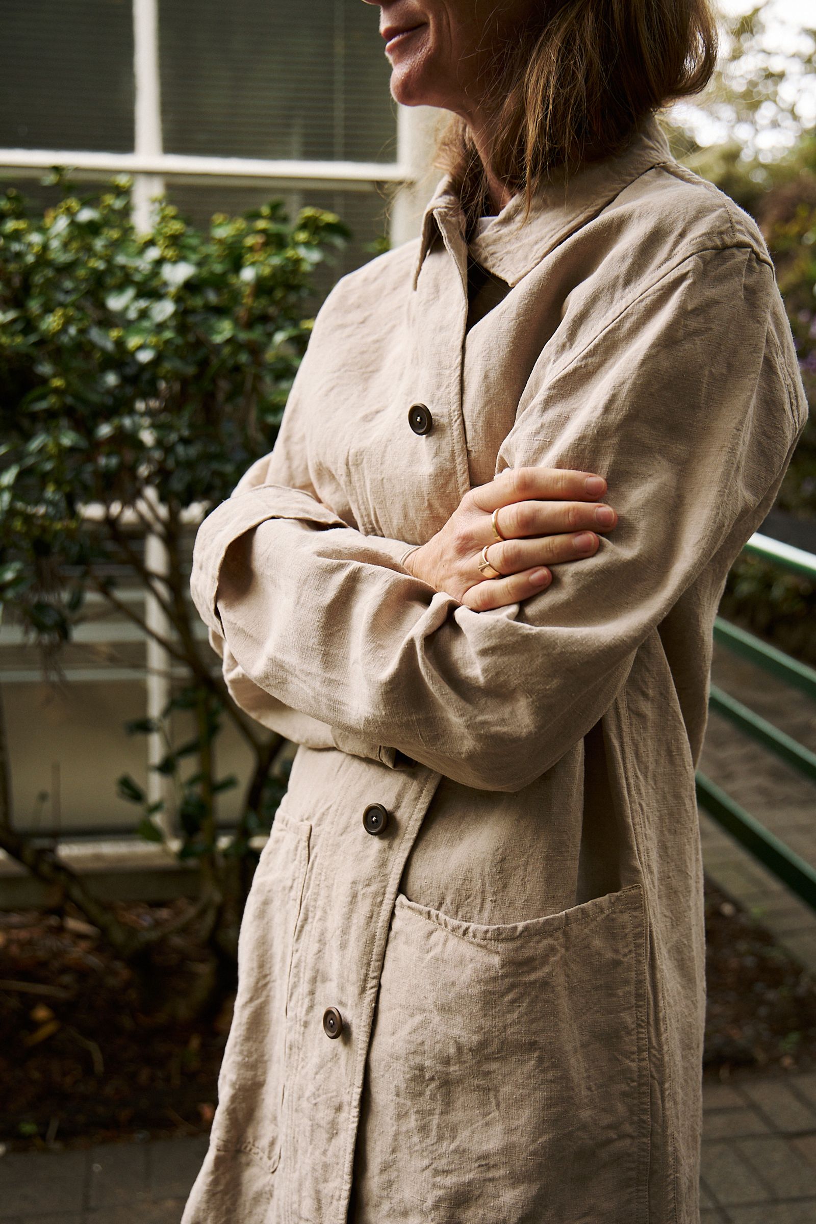 model is wrapped in a linen coat with folded arms
