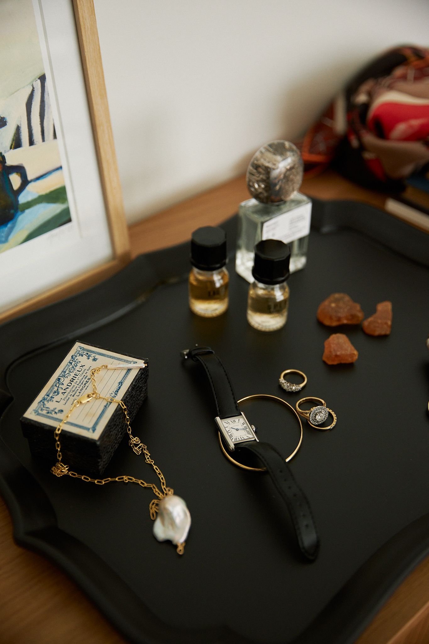 a watch and jewellery lay upon a black tray 