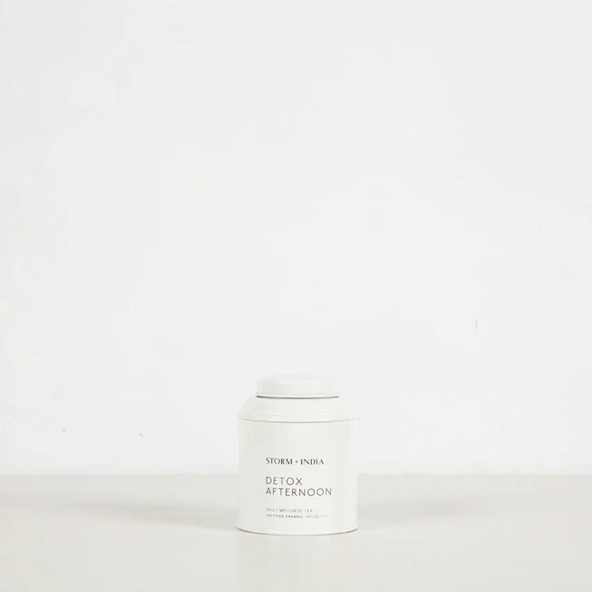 White "STORM + INDIA DETOX AFTERNOON" tea canister on light surface against white background. Minimalist design emphasises clean, simple aesthetic.