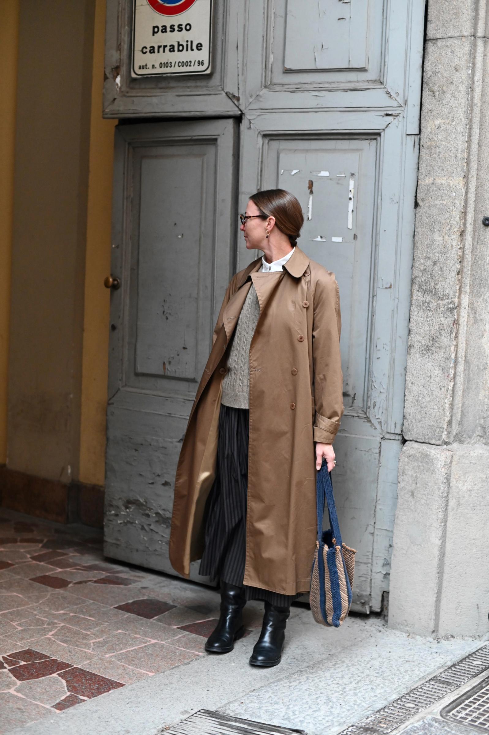 women walking away from a blue door holding a bag and coat