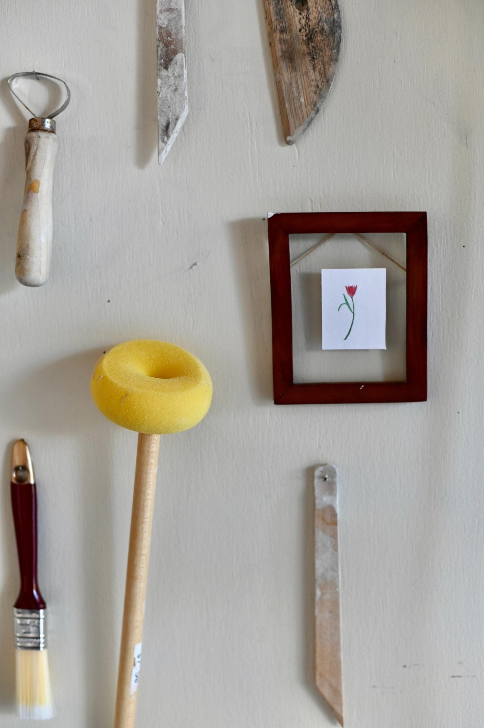 ceramic studio tools such as sponges and wooden palettes hang on wall