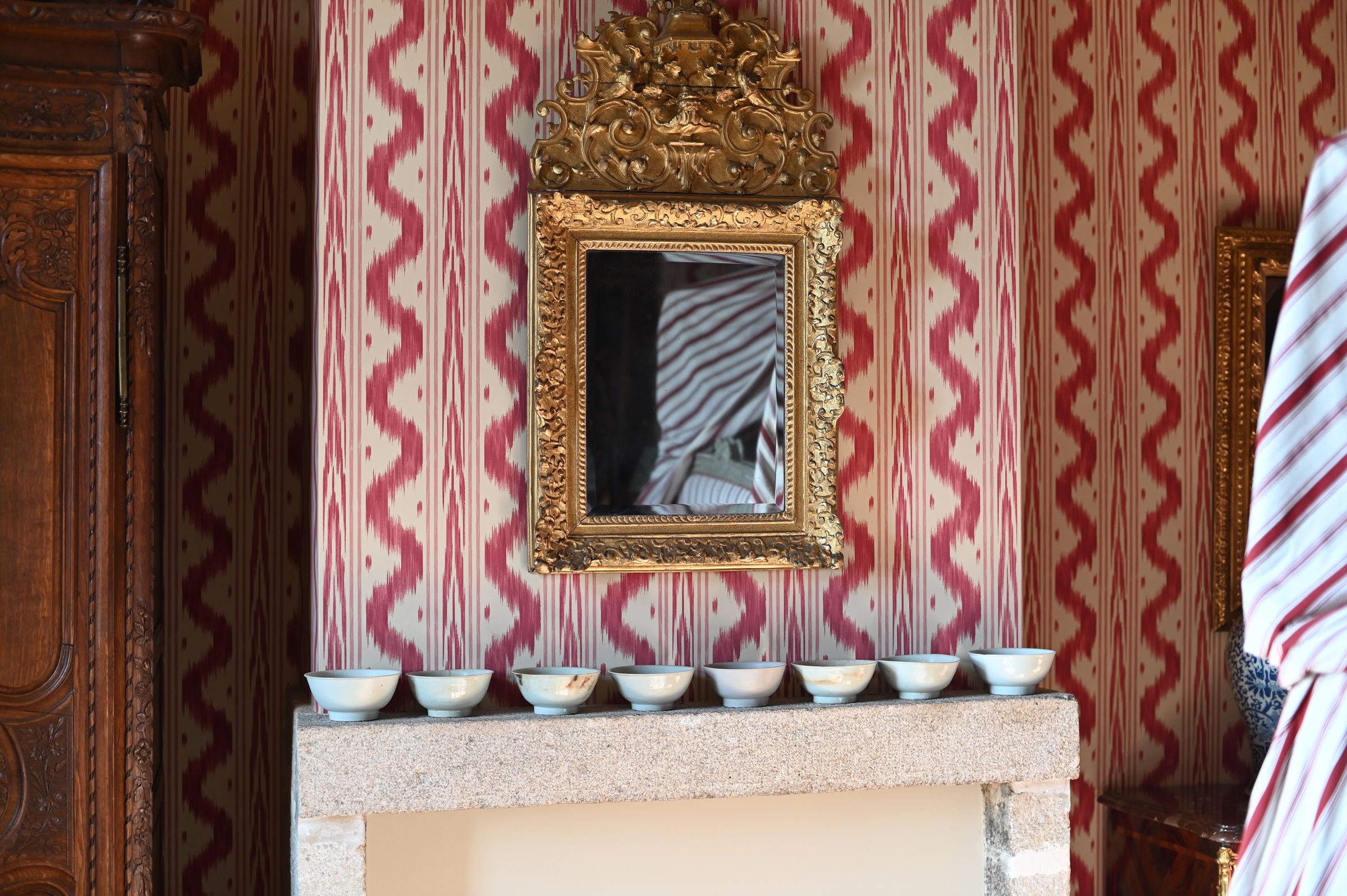 ceramic bowls lined up on the mantlepiece below a gold framed mirror