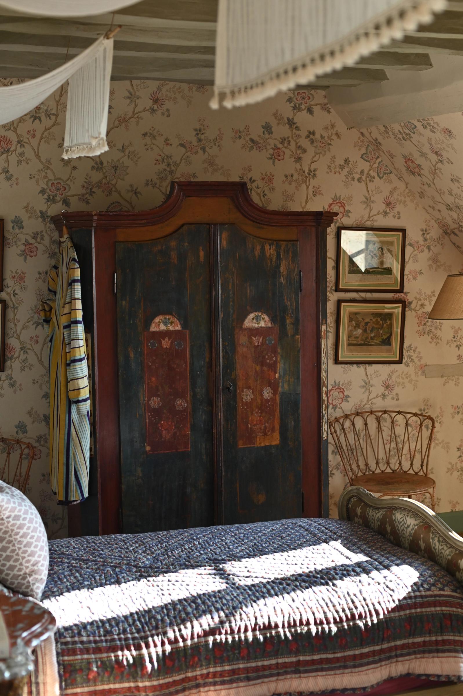 a single bed covered in a quilt and next to an armoire