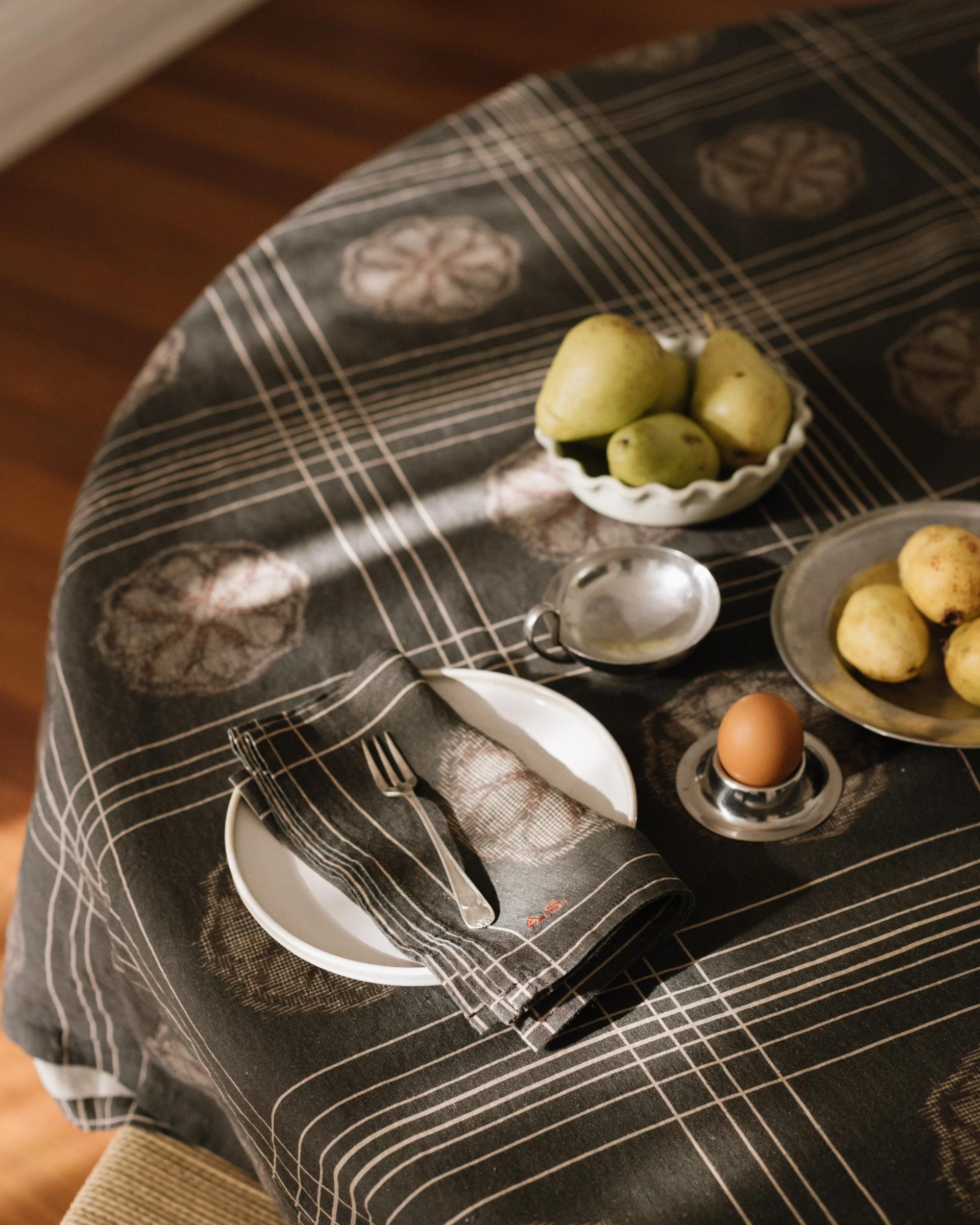 a crop of a round table with grey tablecloth, white plate with napkin and fork