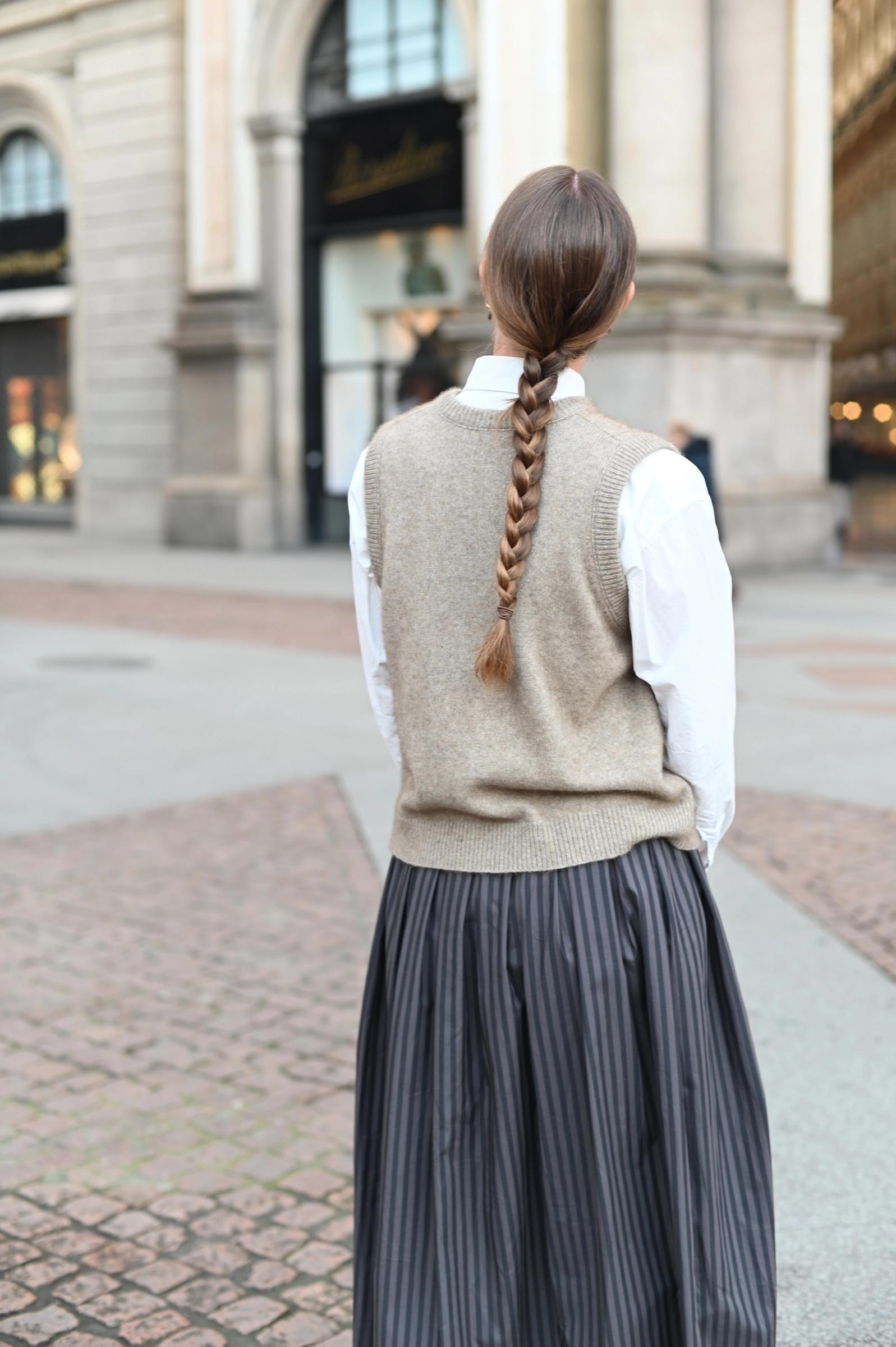 women photographed from behind with a wool vest and braided hair