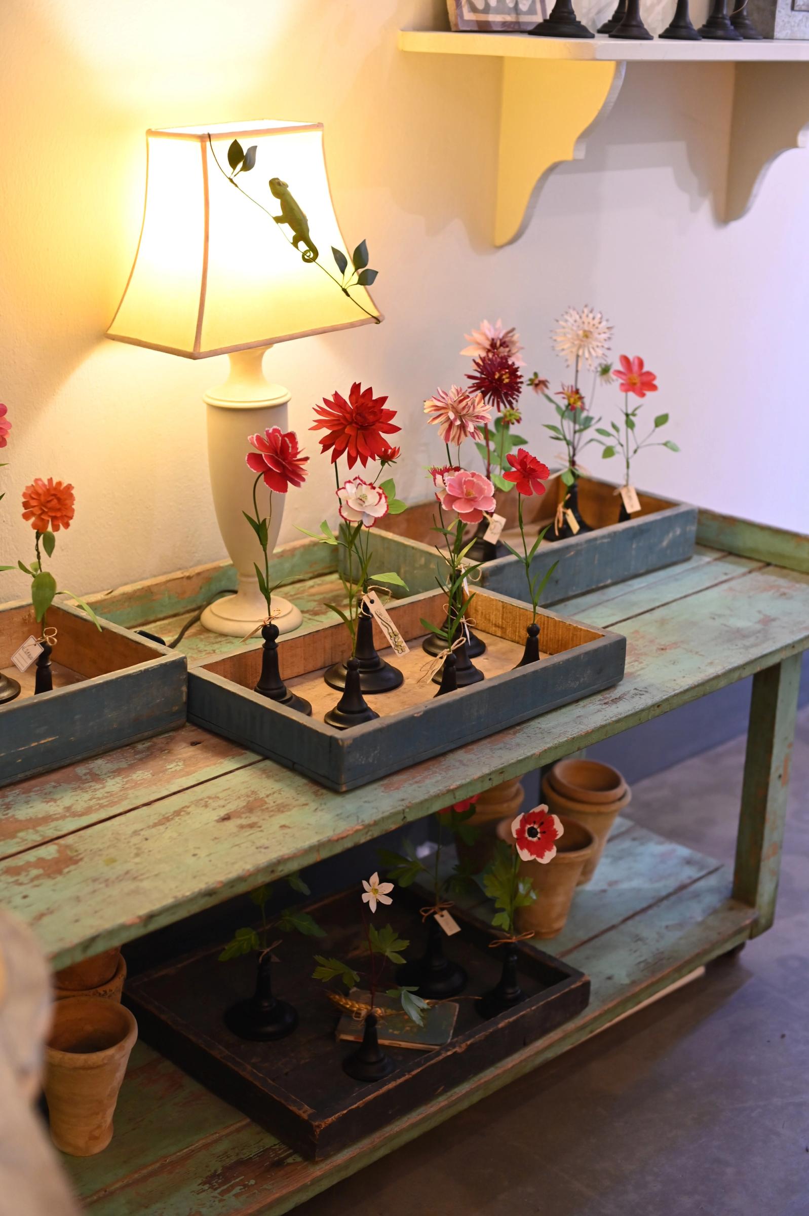 handmade copper flower sculptures on display on a green table