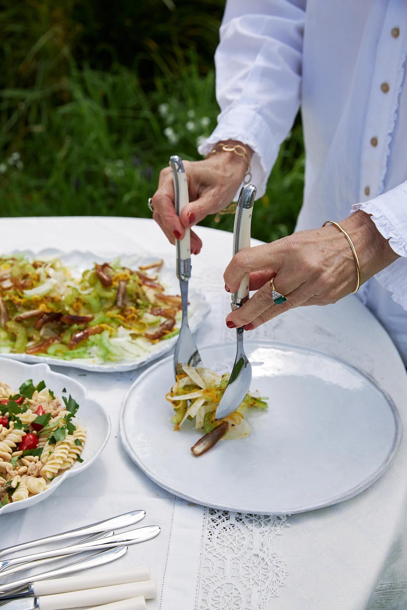 Woman serving a portion of salad from platter onto her place in the garden