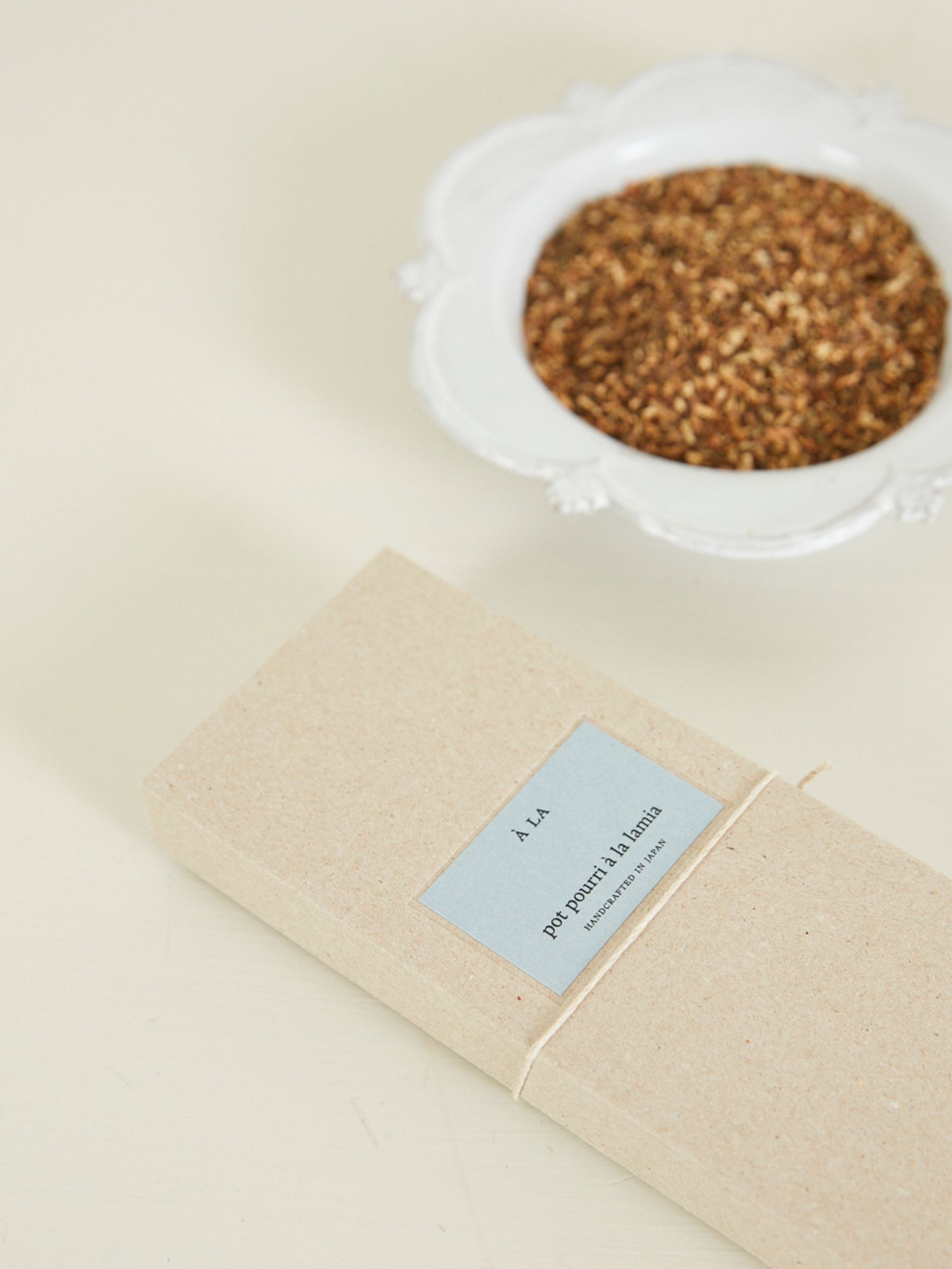 a branded box sits next to a white bowl of pot pourri 