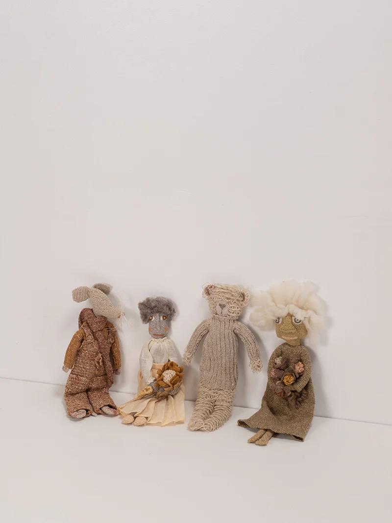  Four handcrafted dolls, each with unique designs, sit against a plain background. The dolls include a bear, a bouquet holder, and one with fluffy hair, all by Sophie Digard.