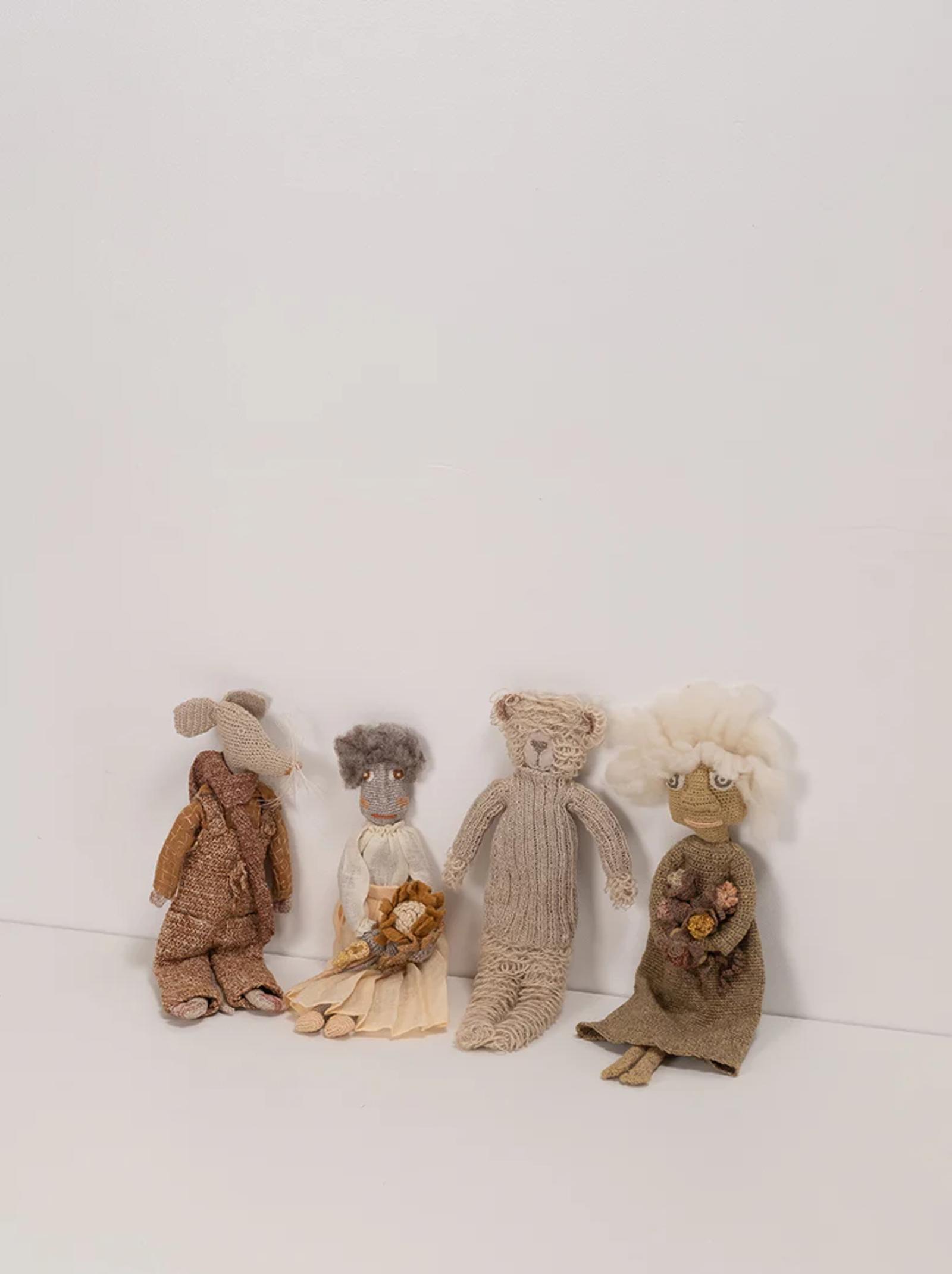 Four handcrafted dolls, each with unique designs, sit against a plain background. The dolls include a bear, a bouquet holder, and one with fluffy hair, all by Sophie Digard.