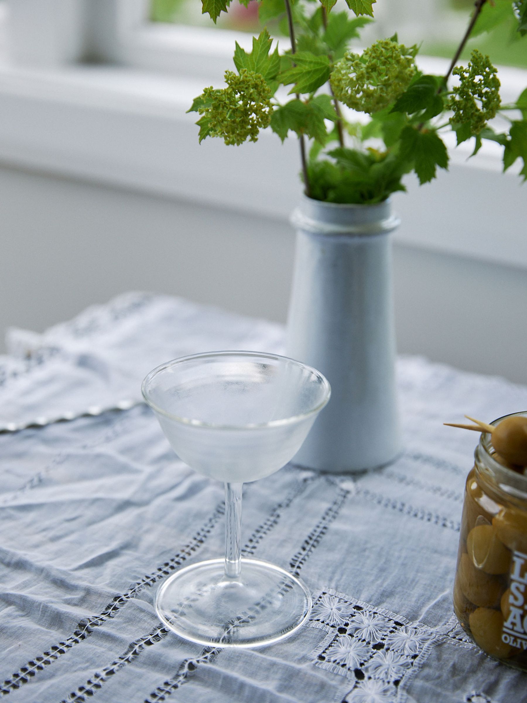 Martini glass chilled on side table with lace cloth beside window