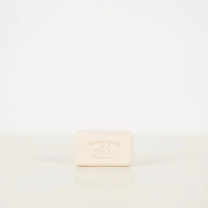 Pré de Provence soap bar in Astier de Villatte ceramic dish. Light beige soap with engraved brand name against white background.