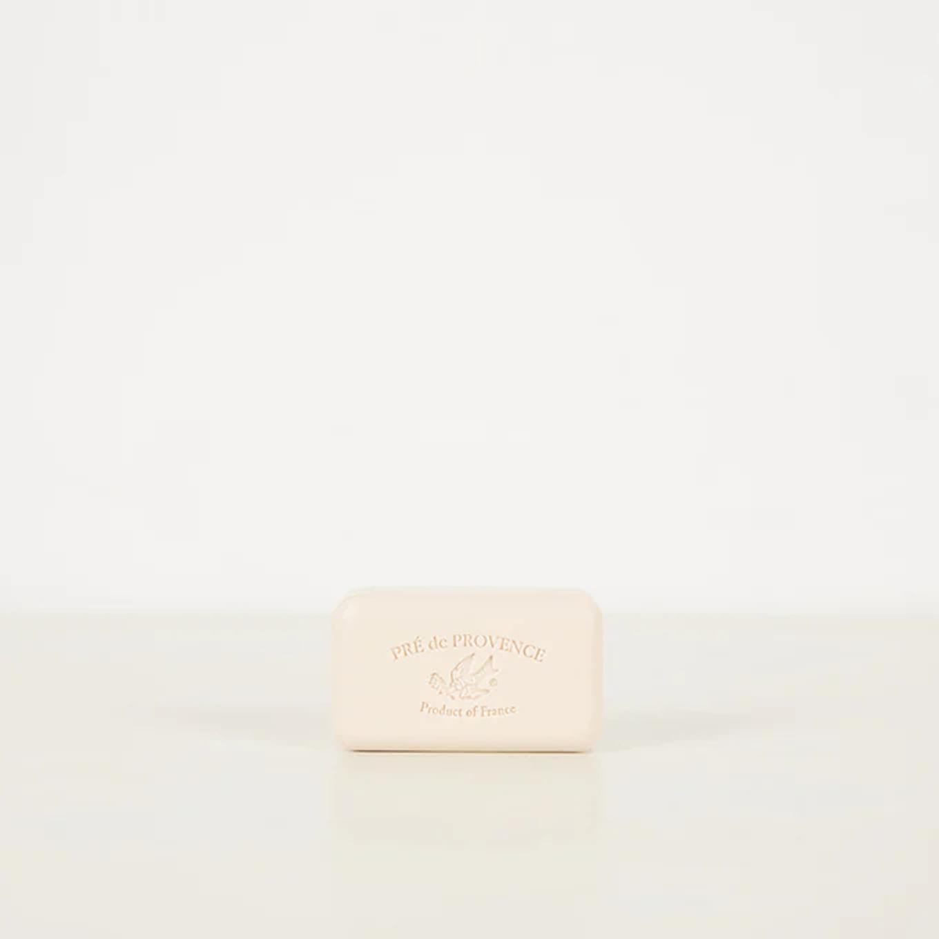 Pré de Provence soap bar in Astier de Villatte ceramic dish. Light beige soap with engraved brand name against white background.