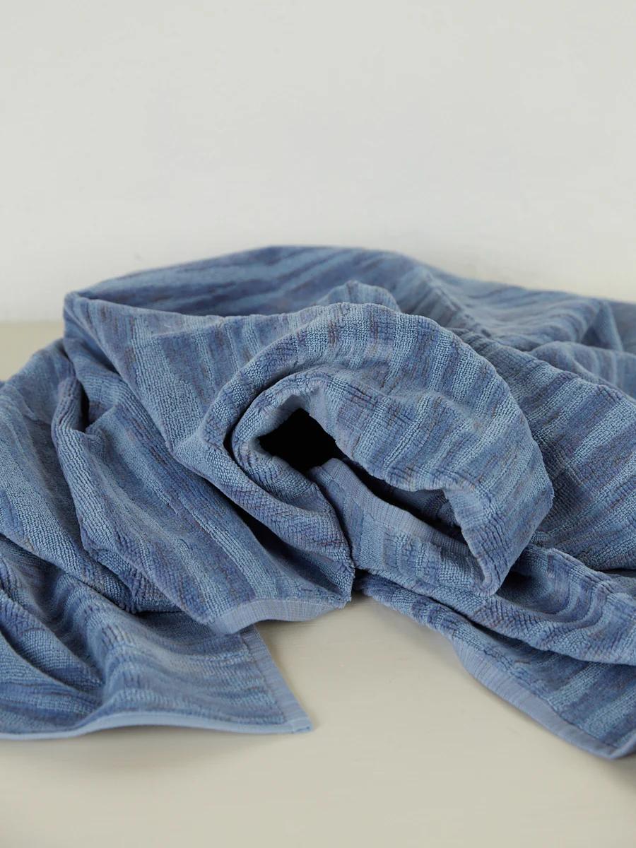 A crumpled blue towel with a textured, striped pattern lies on a light surface, adding elegance to the space.