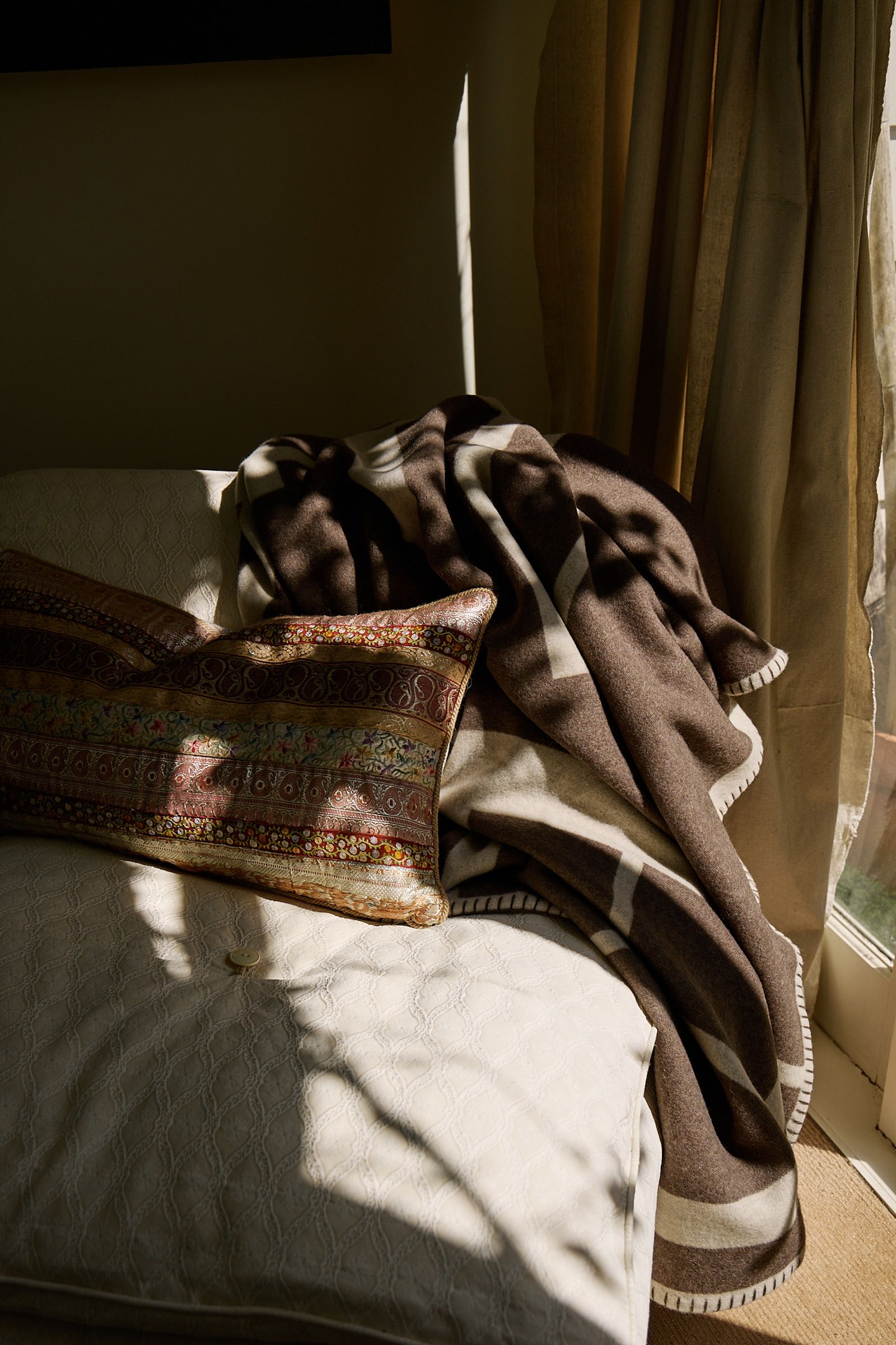 blanket and cushion lay sprawled in the sun on a couch