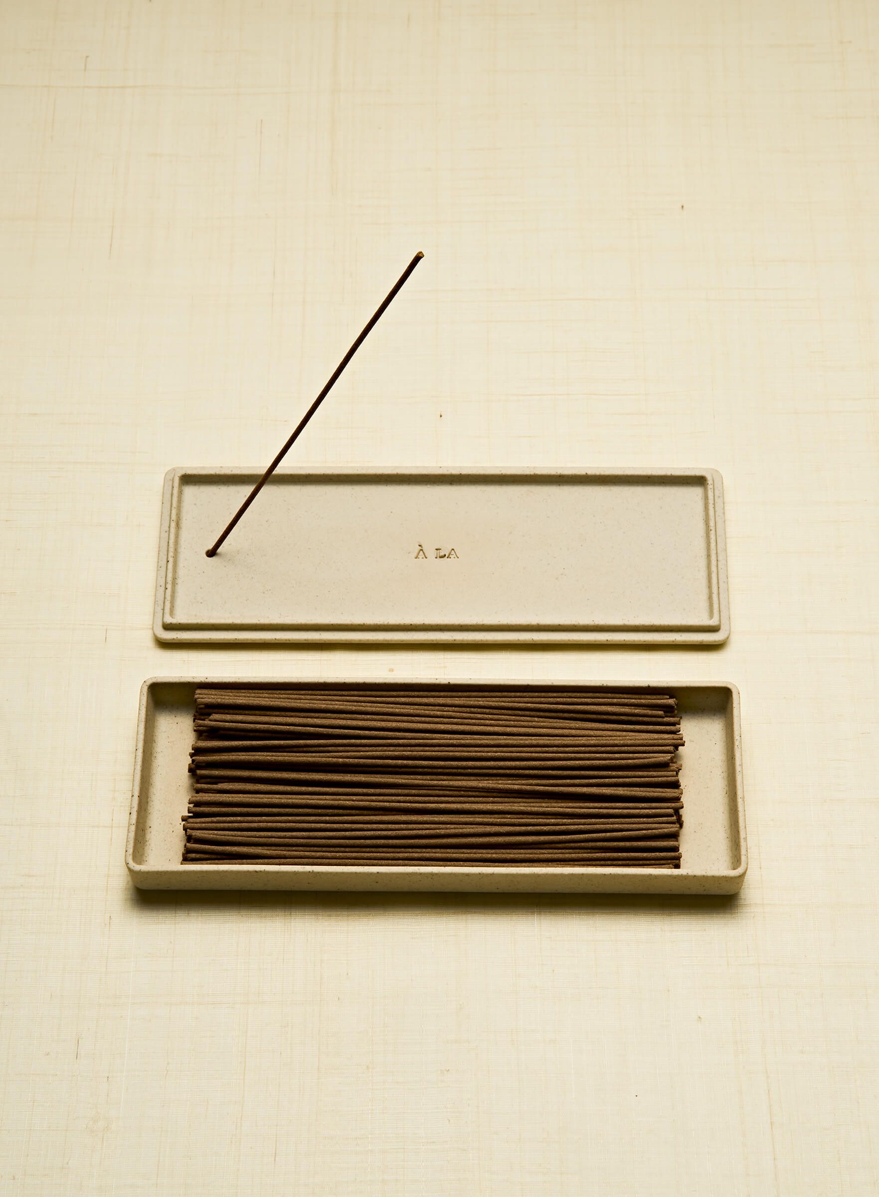 a porcelain box is open revealing brown incense sticks 