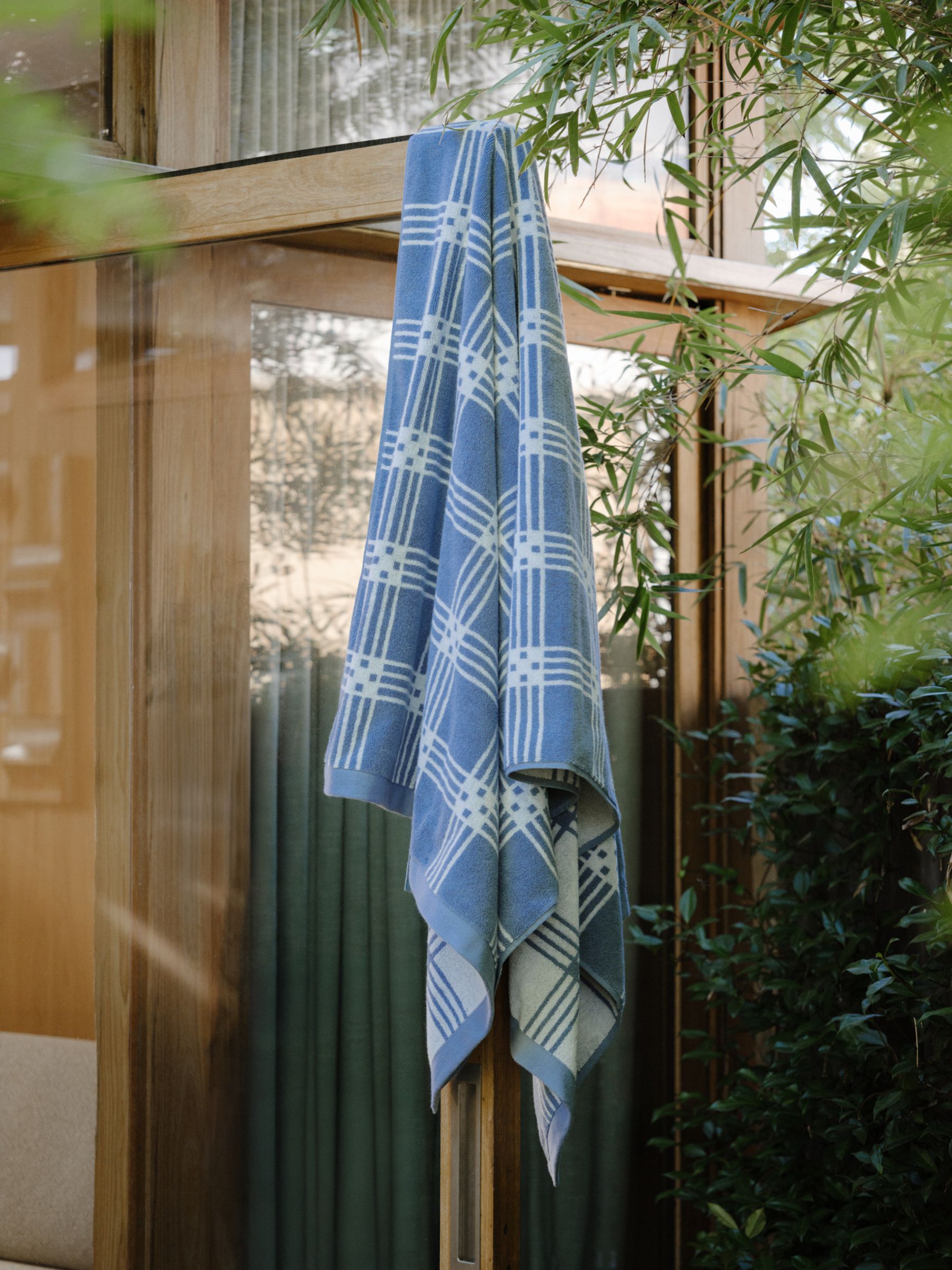 a tartan bain towel hangs over the home door next to trees