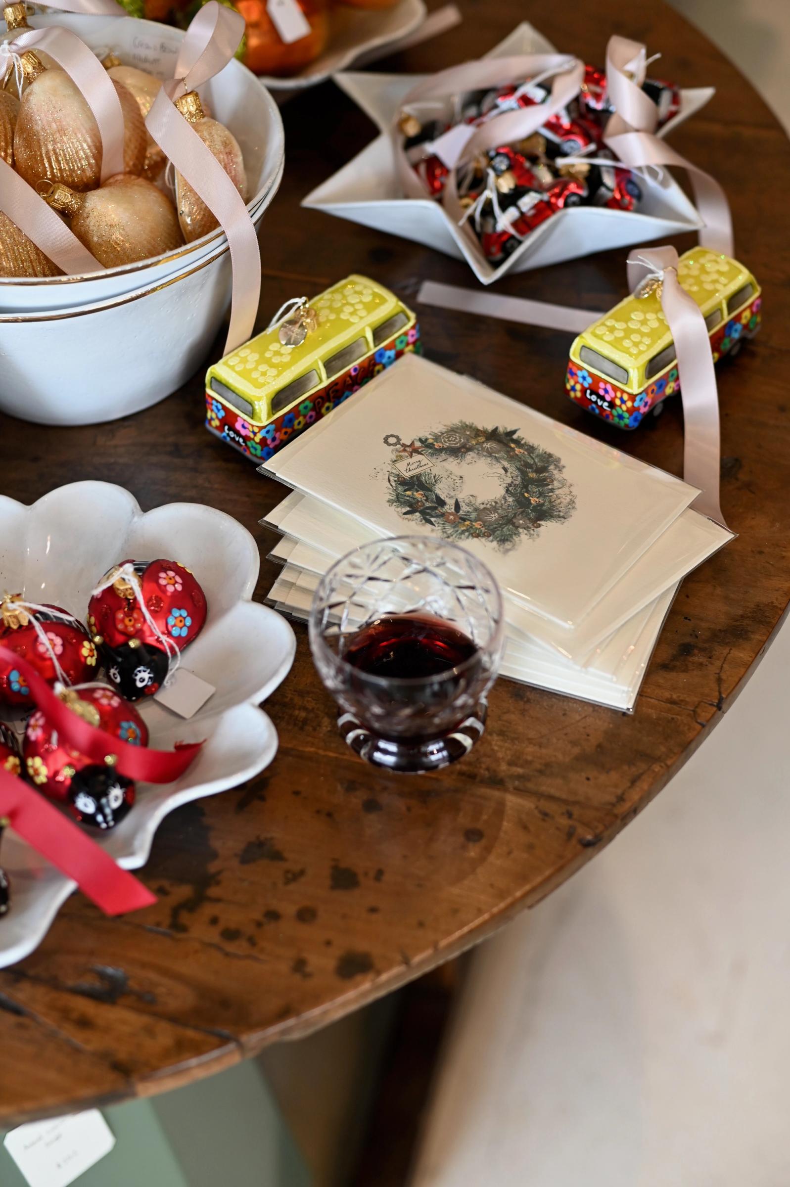 table filled with christmas decorations, flowers, and a glass of wine