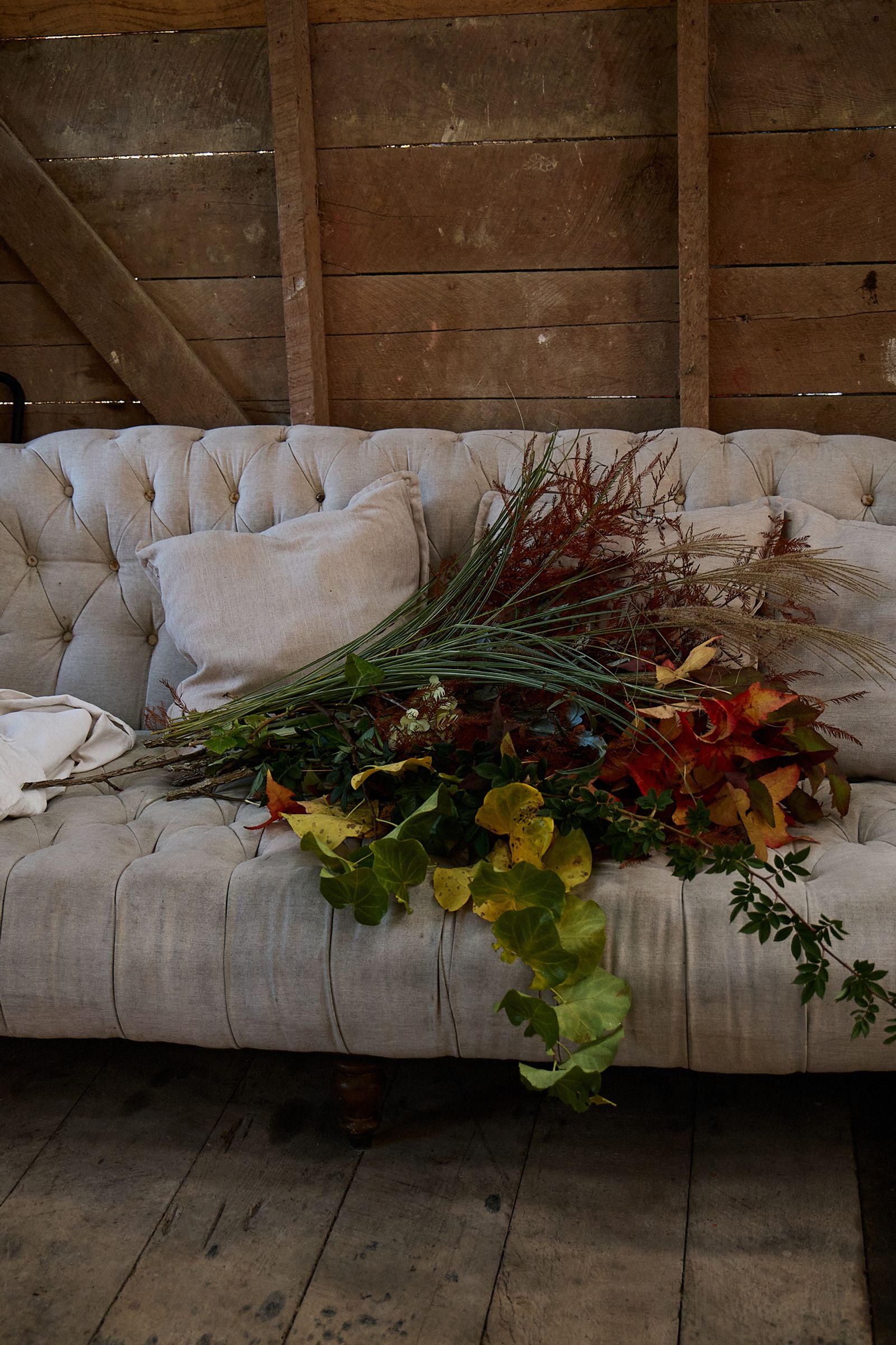 couch strewn with blooms and foliage in the flower barn