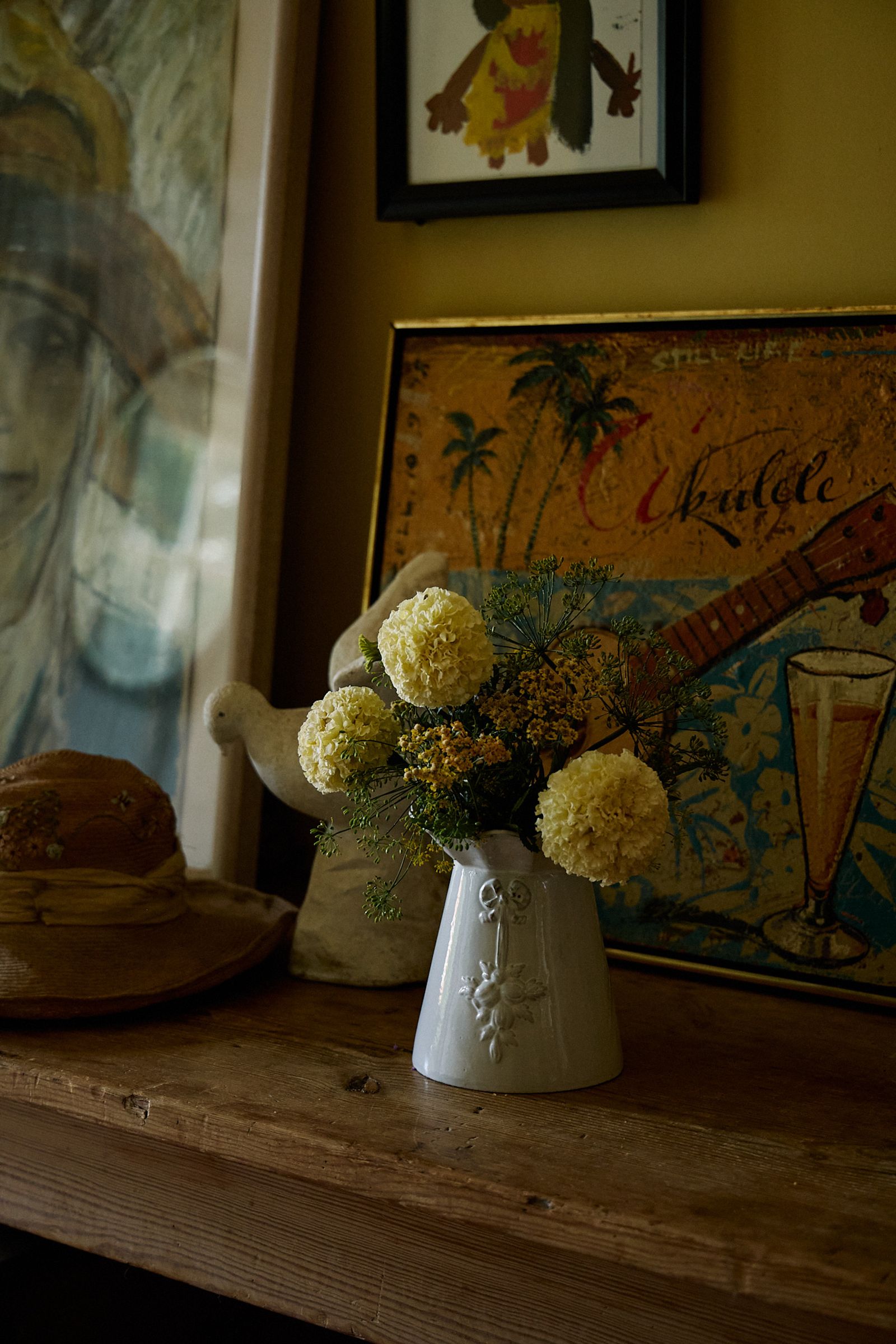 marigold flowers in a white vase at home entrance against paintings