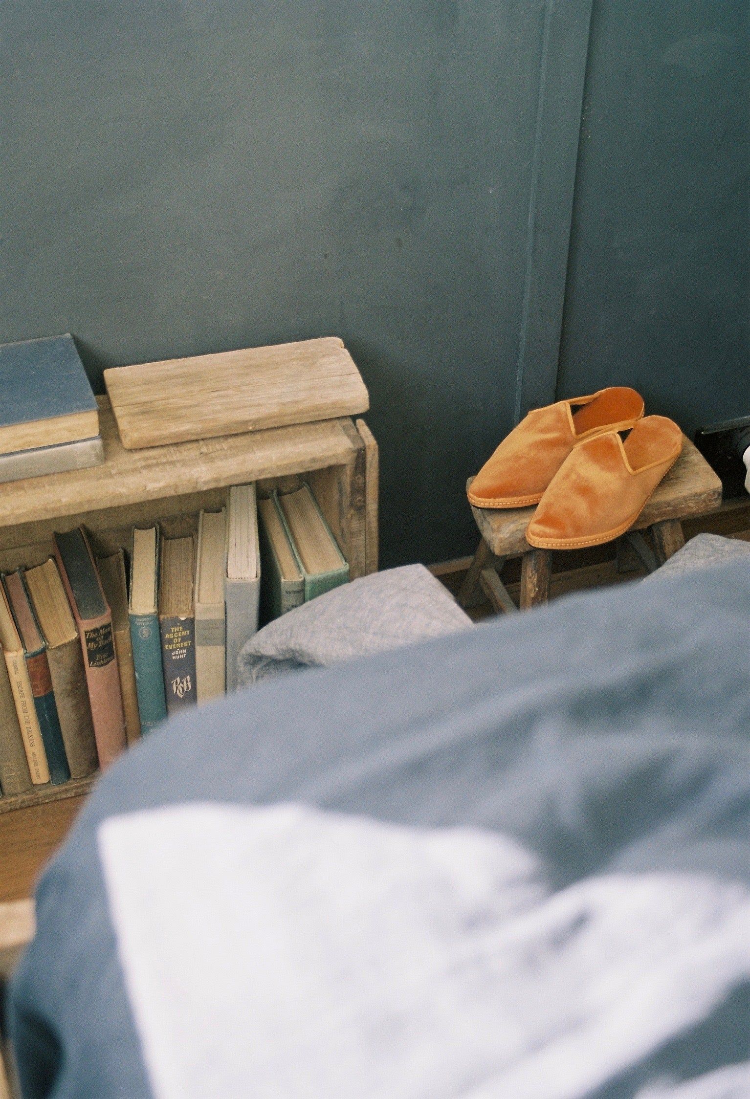 A cozy seaside cottage scene with a bookshelf, slippers, and pyjamas beside an unmade bed, creating a warm and inviting setting.