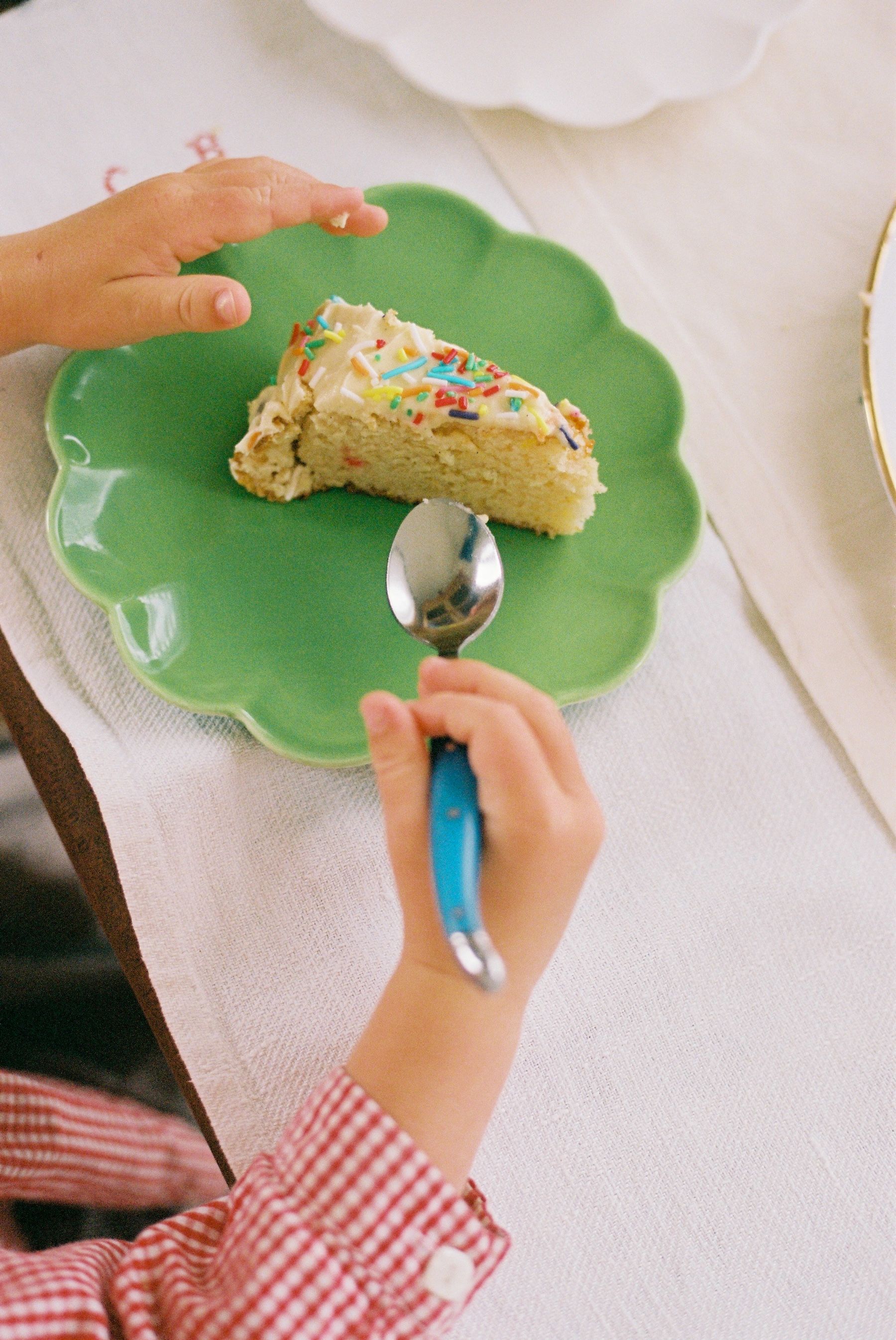 small boy attempts to eat his slice of cake from a green plate