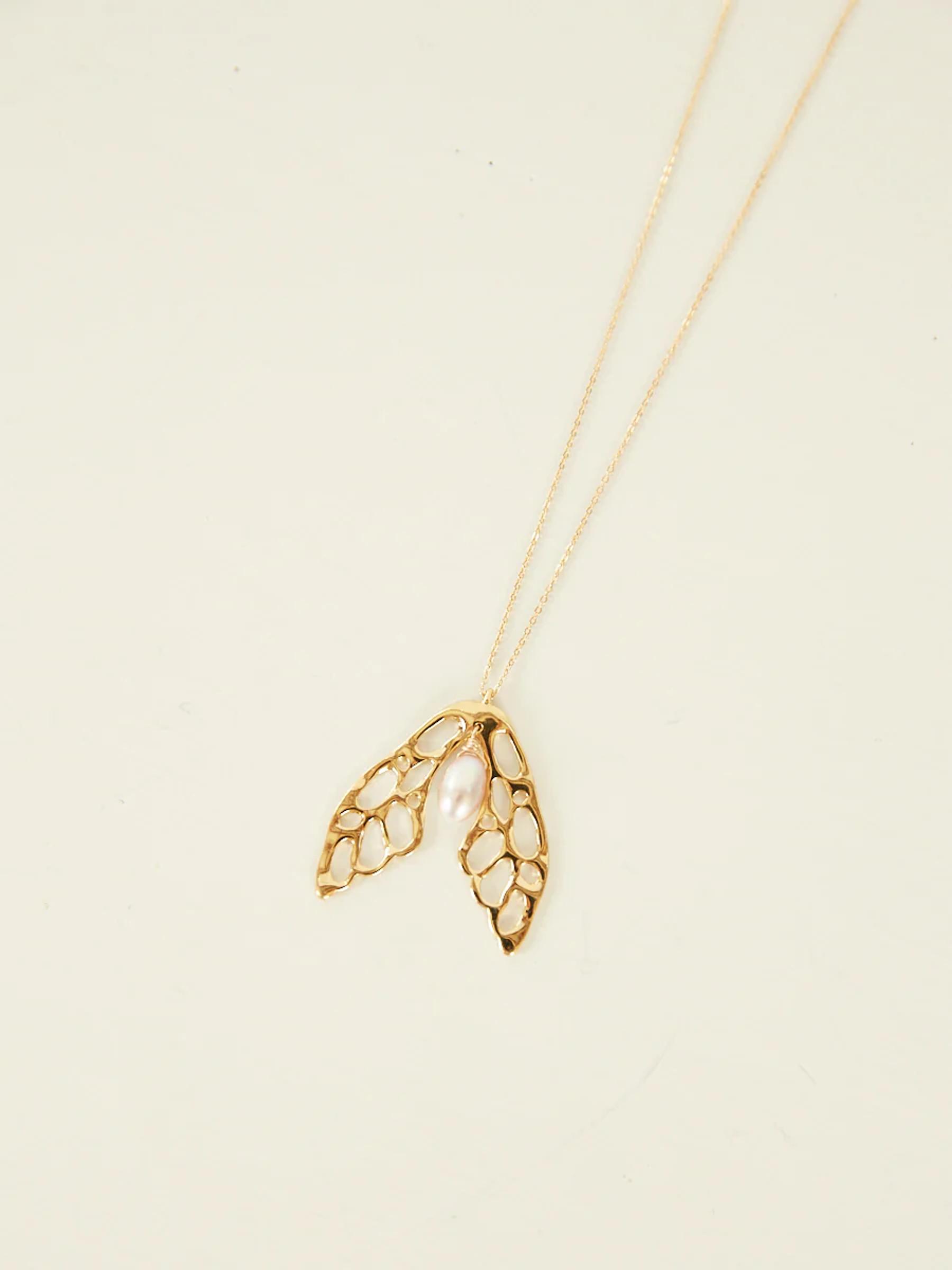Gold necklace with wing-like pendant featuring honeycomb structure and small pearl. Suspended from fine gold chain.