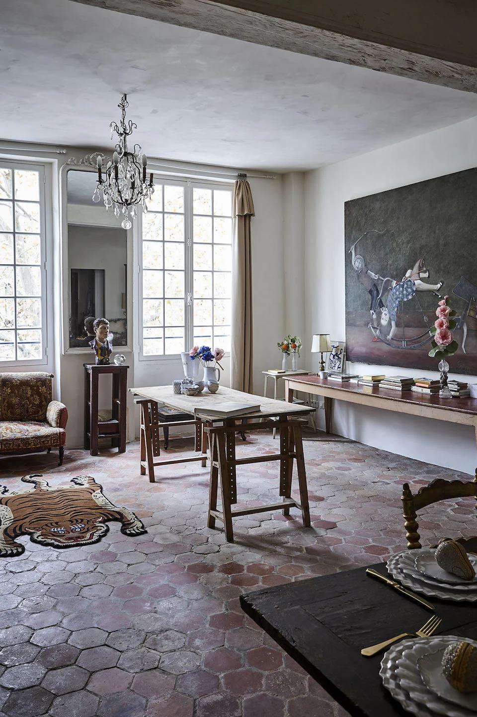 Spacious room with hexagonal tiles, animal painting, and chandelier. Wooden tables, vintage furniture, and decorative items like a tiger rug create an elegant anthology.