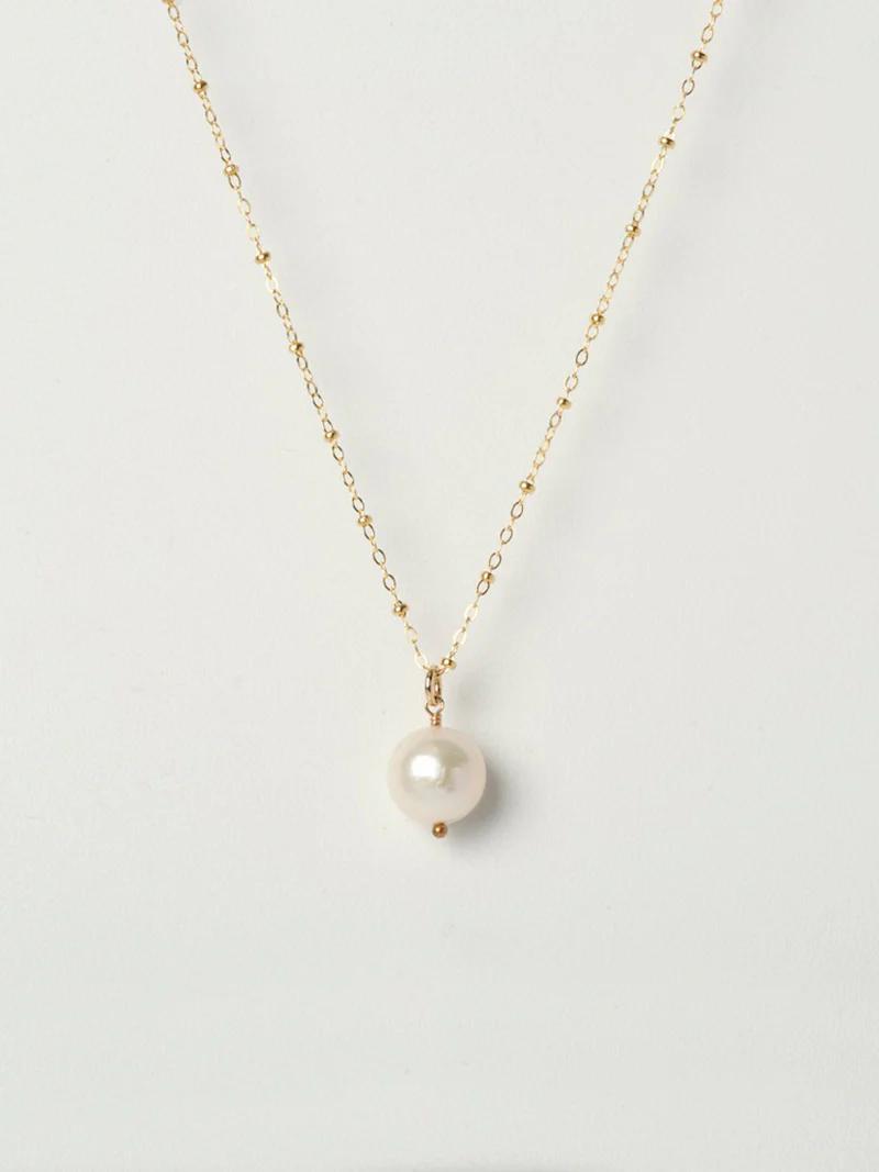 A delicate gold chain necklace with gold beads and a single round pearl pendant displayed on a plain white background.