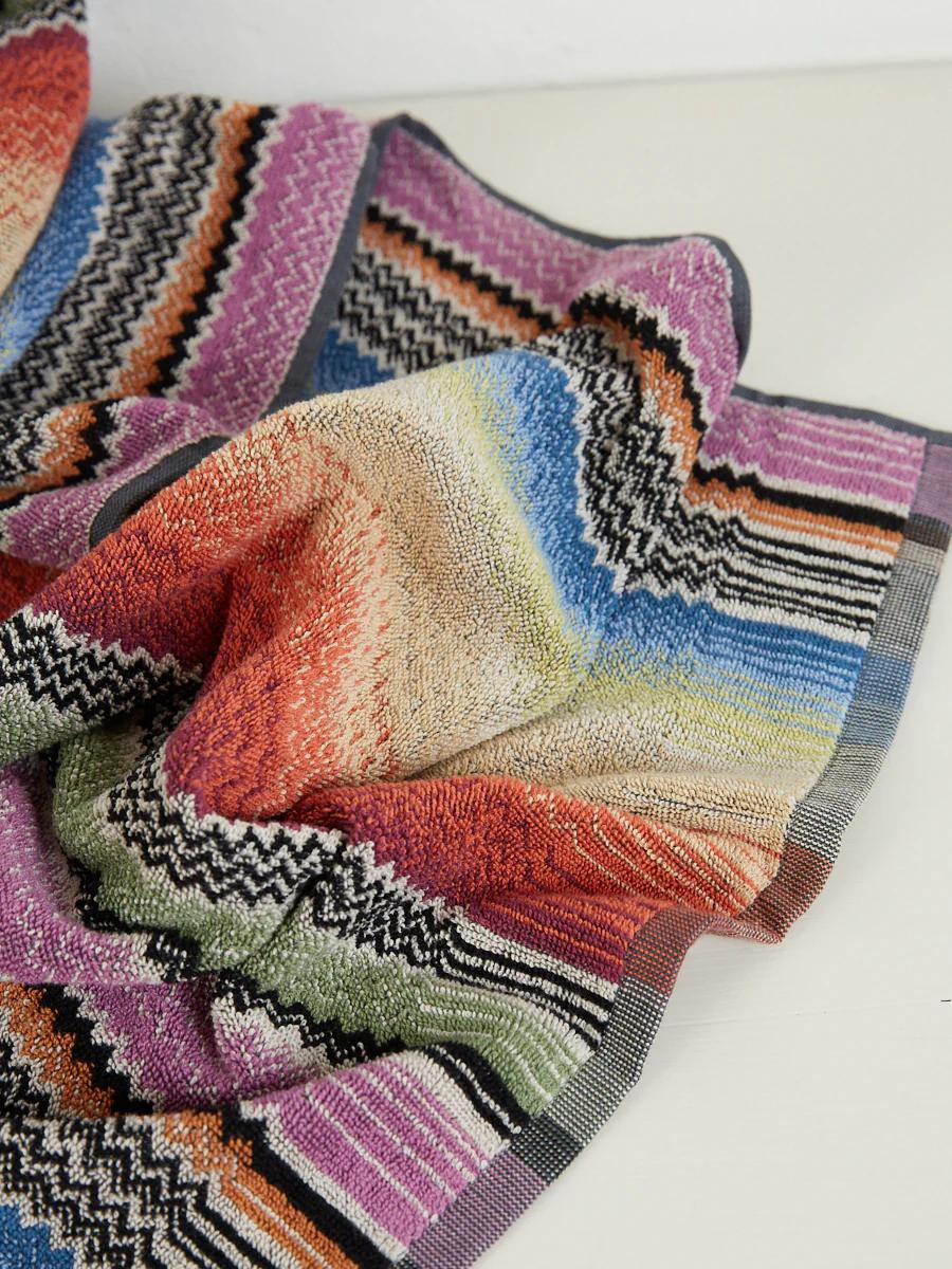 A colourful woven textile with intricate patterns and stripes in purple, pink, orange, red, green, blue, and black, from Missoni’s collection.