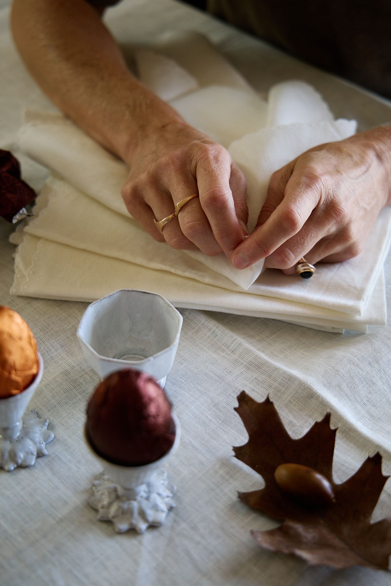 hands on a stack of white napkins and easter eggs in egg cups