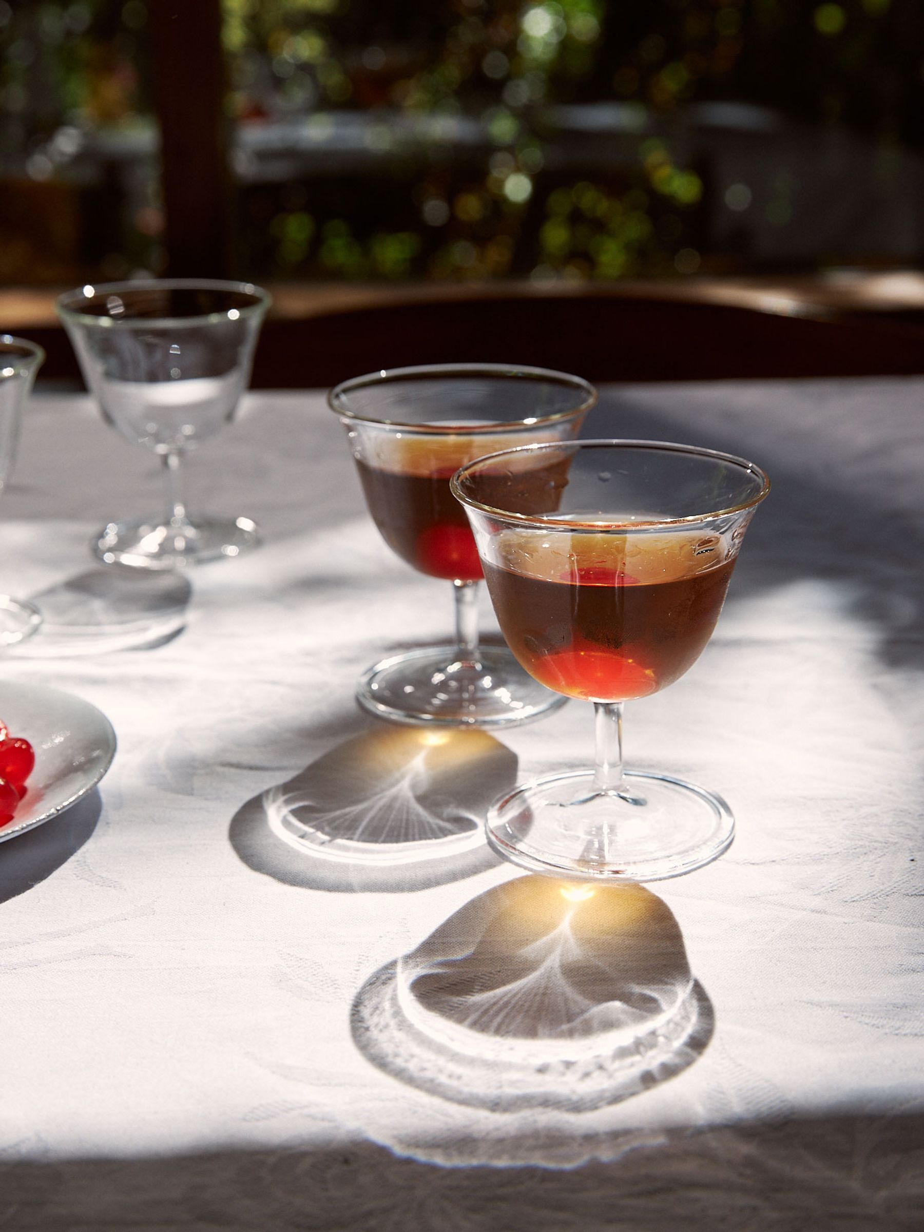 Rosseta Sour glasses on a sunlit table with cherries in the summer cocktail