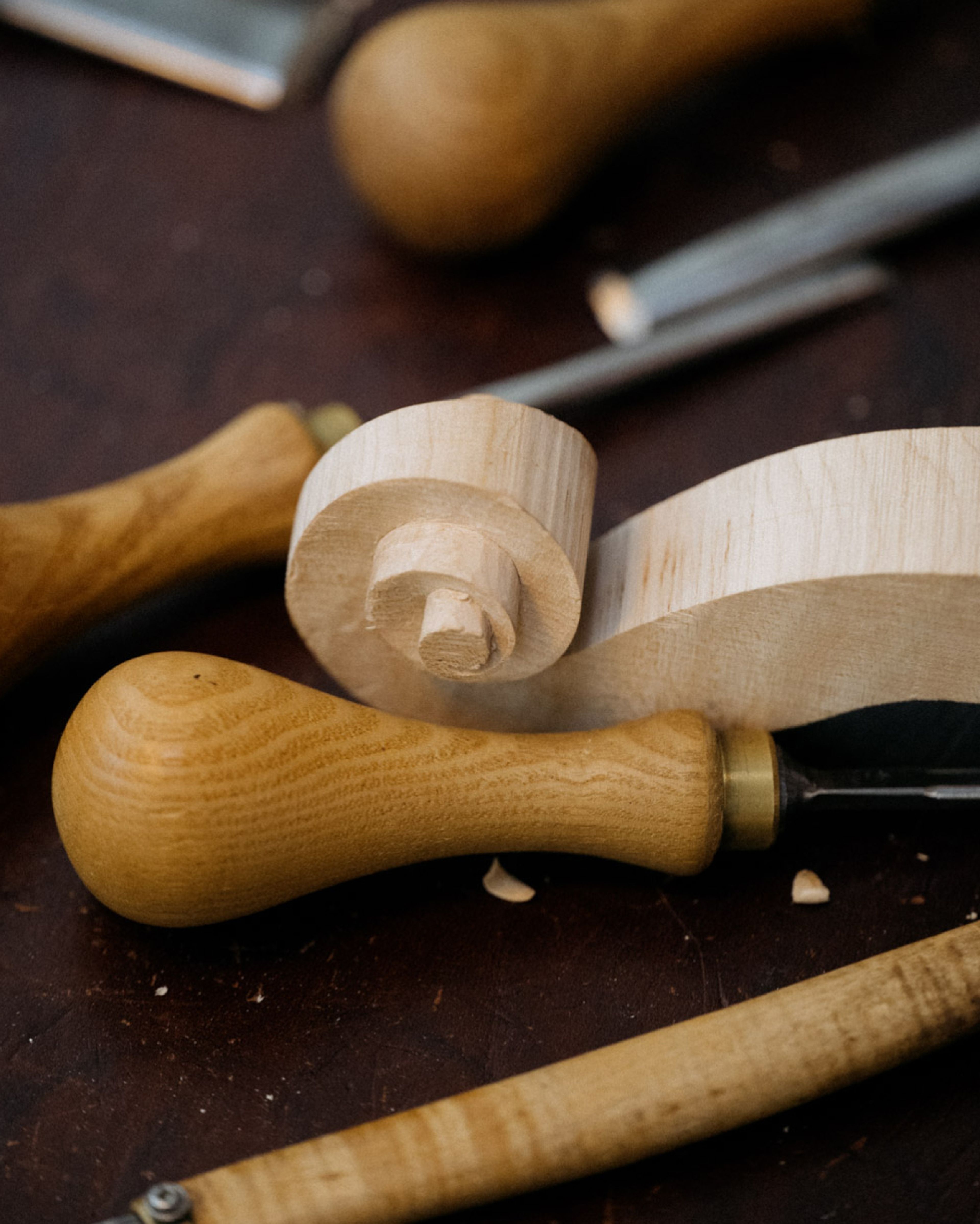 Unfinished violin scroll among carving tools.