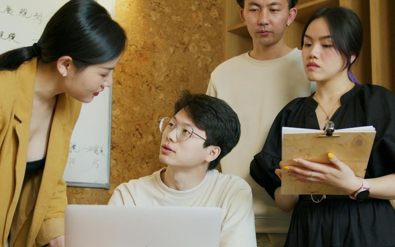 Group of people listening attentively, one of them taking notes during the meeting
